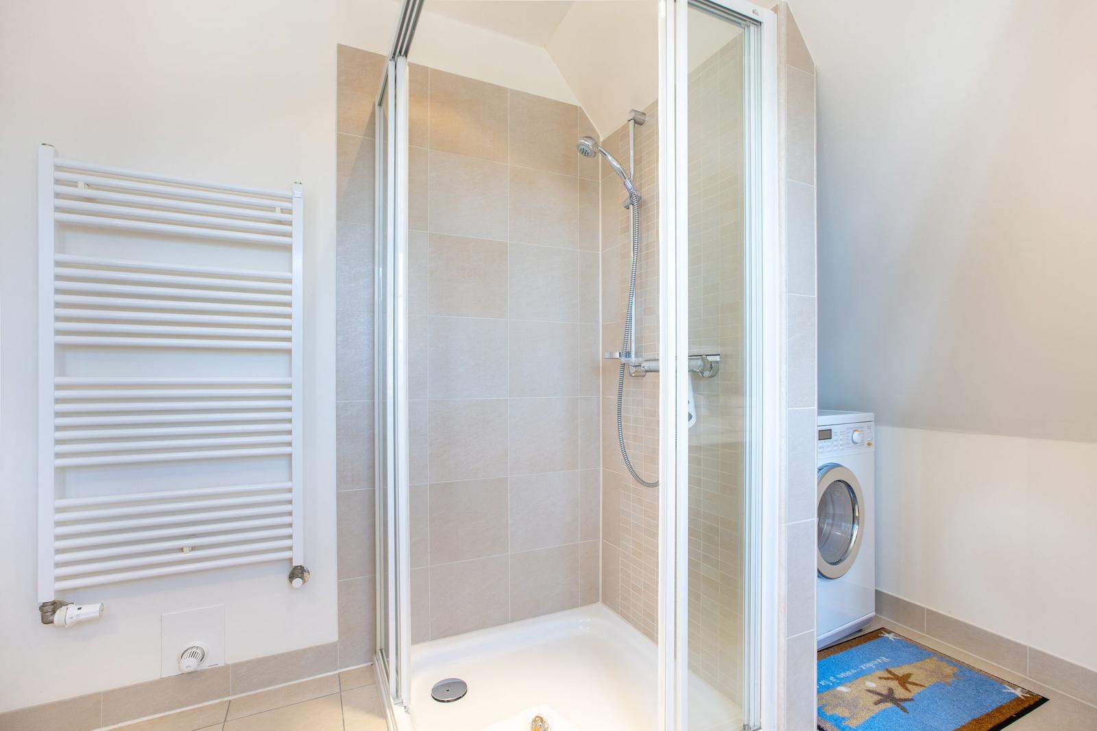 Dusche mit Duschbrause, Heizung und Waschmaschine im Bad