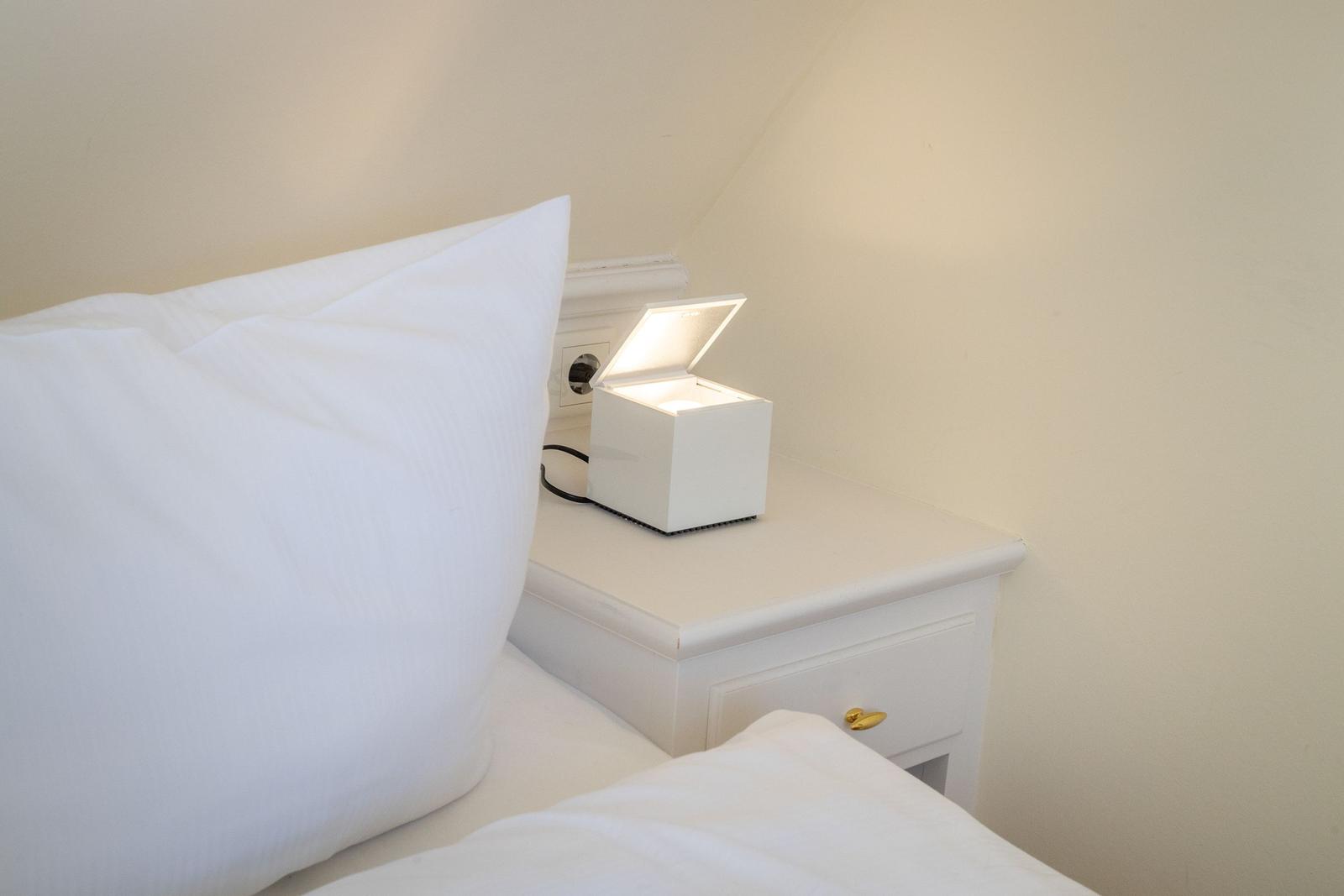 Weißes Nachttischchen mit Nachttischlampe und Kissen