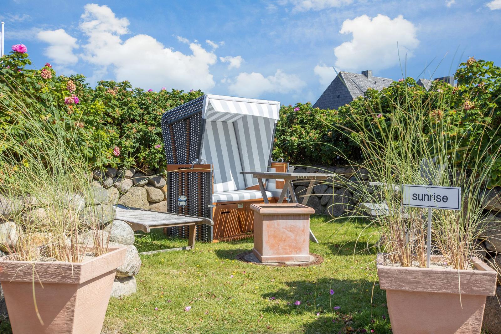 Garten mit Strandkörbe, Tisch, Pflanzen und Schild sunrise.
