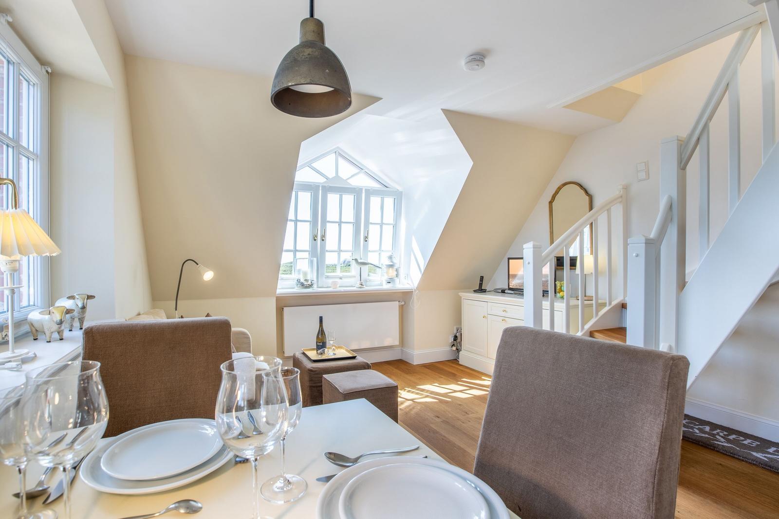 Esszimmer mit Tisch, Stühlen und Blick auf Treppenhaus und Fenster