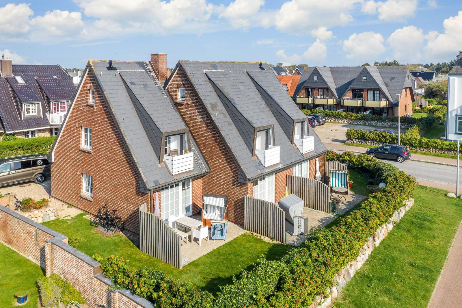 Red brick house with roof terraces and garden area.