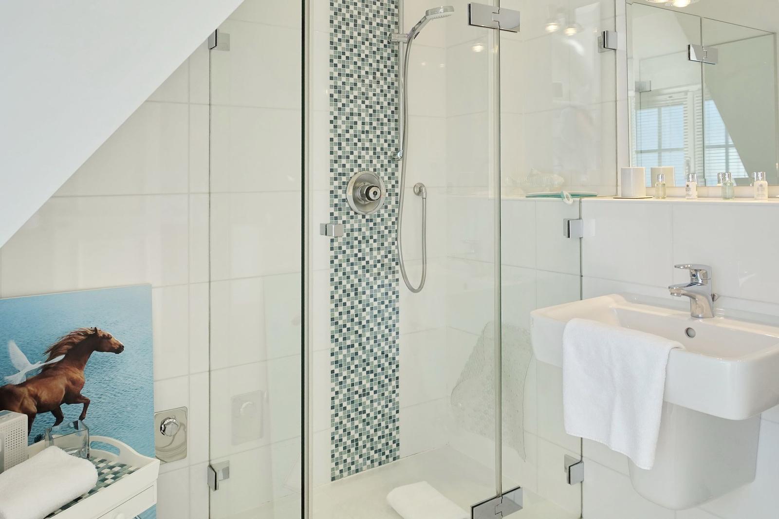 Shower with glass enclosure, sink, and wall art with horse.