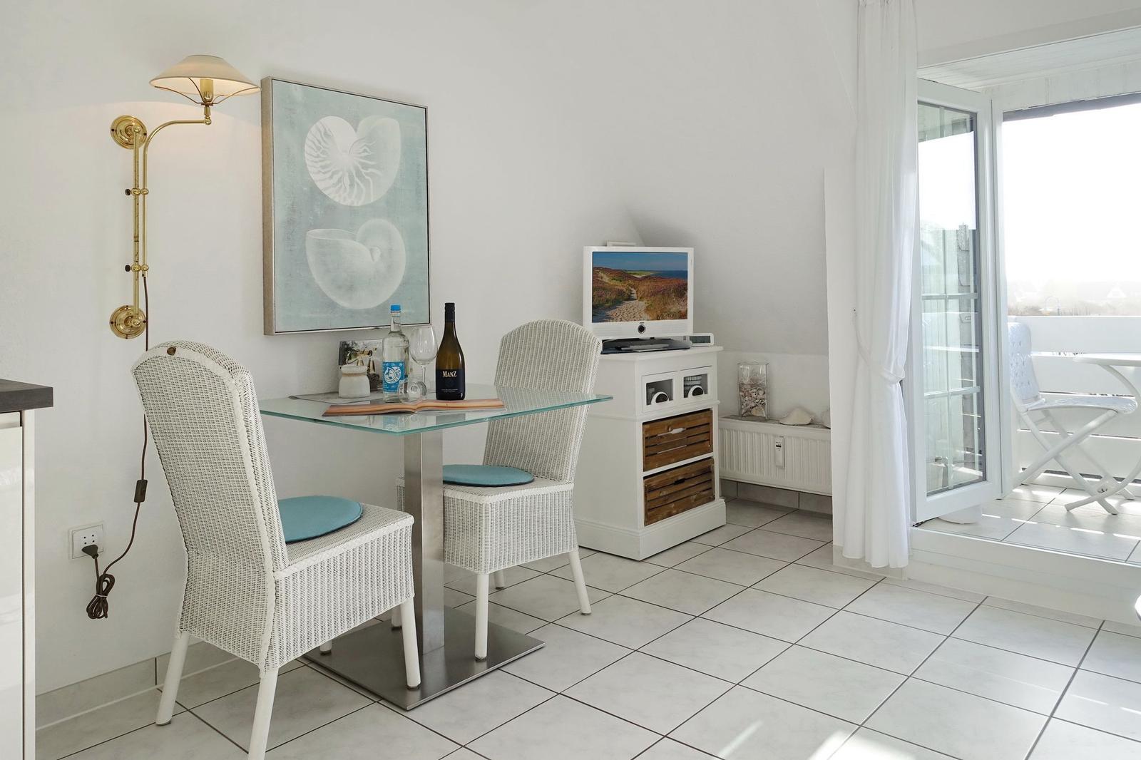 Dining area with glass top, white chairs, and TV. Terrace with seating.