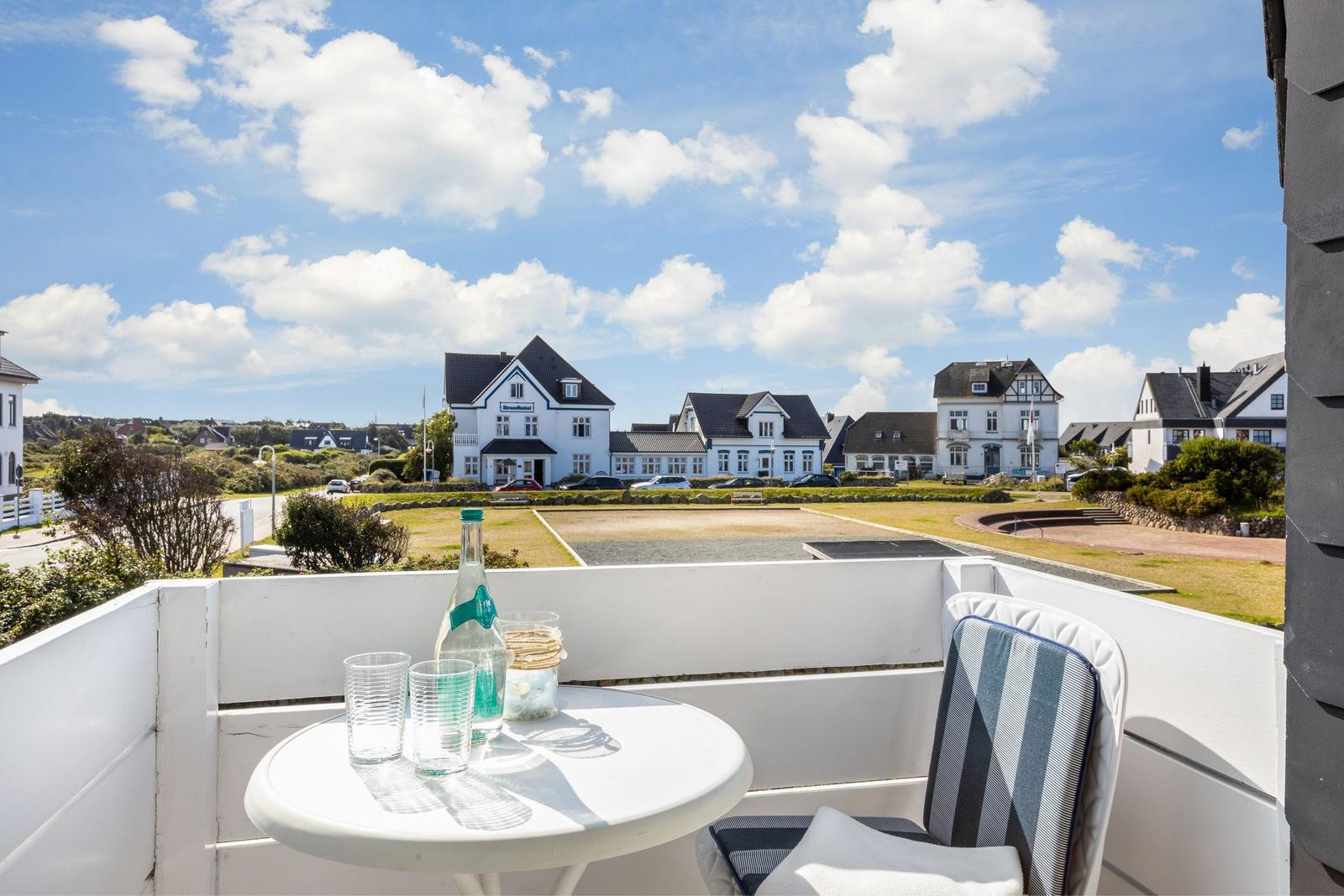 Terrace with table and chair. View of white houses and green landscape.