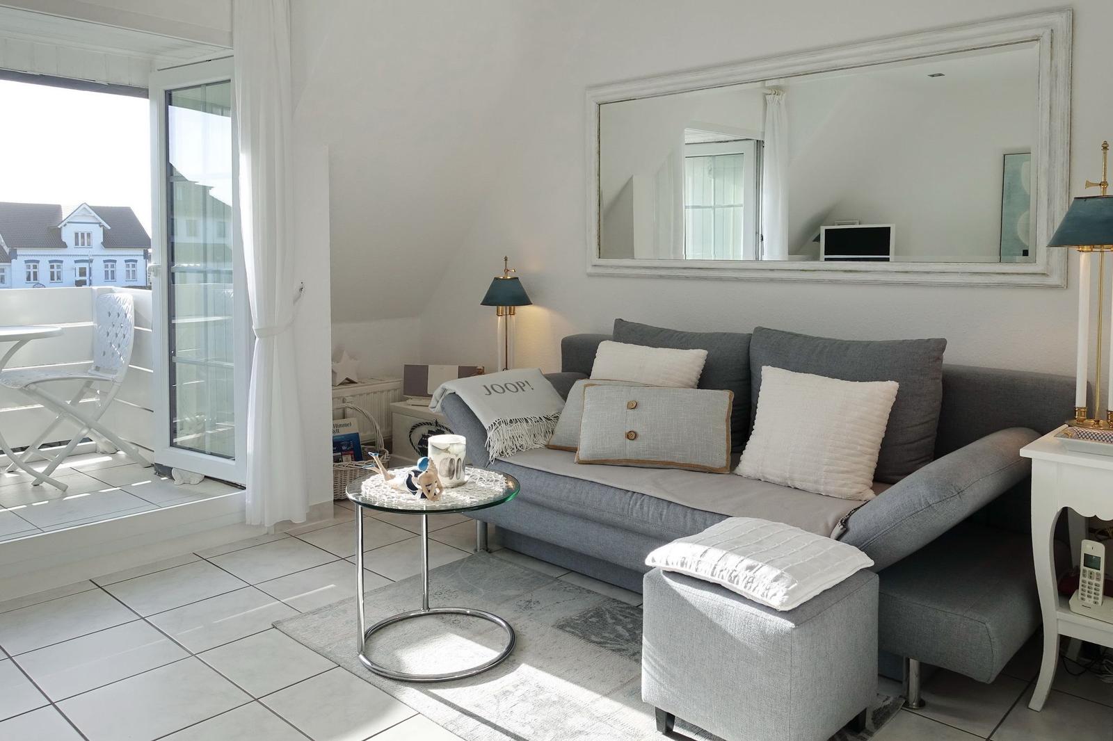 Living room with sofa, mirror, and balcony access.