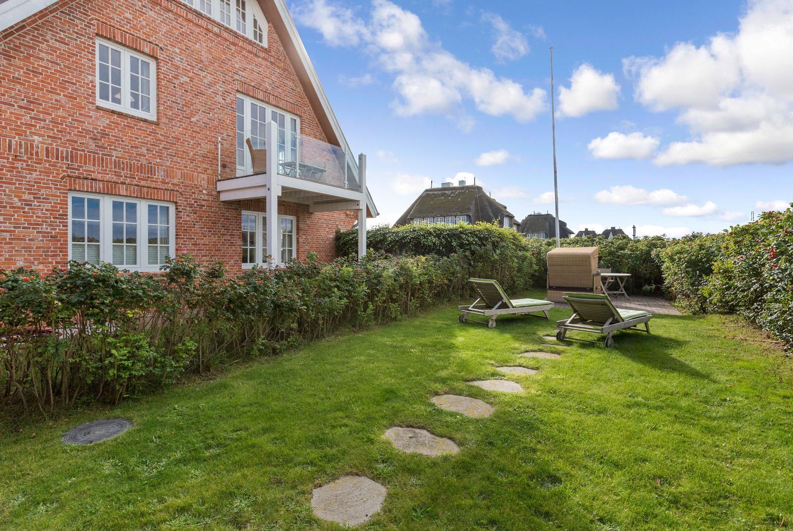 Red brick house with terrace and garden with sun loungers.