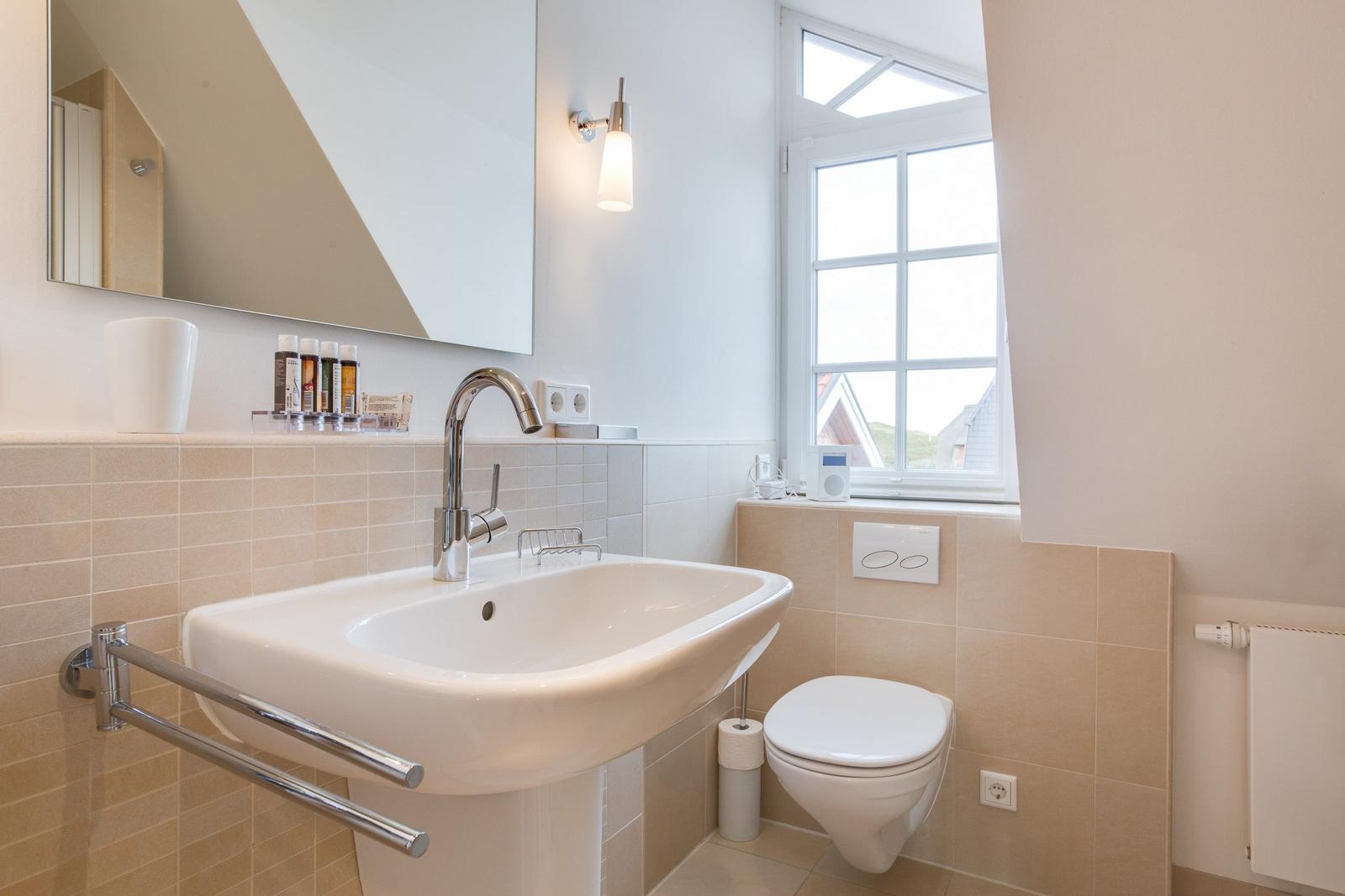 Bathroom with sink, toilet, and window.