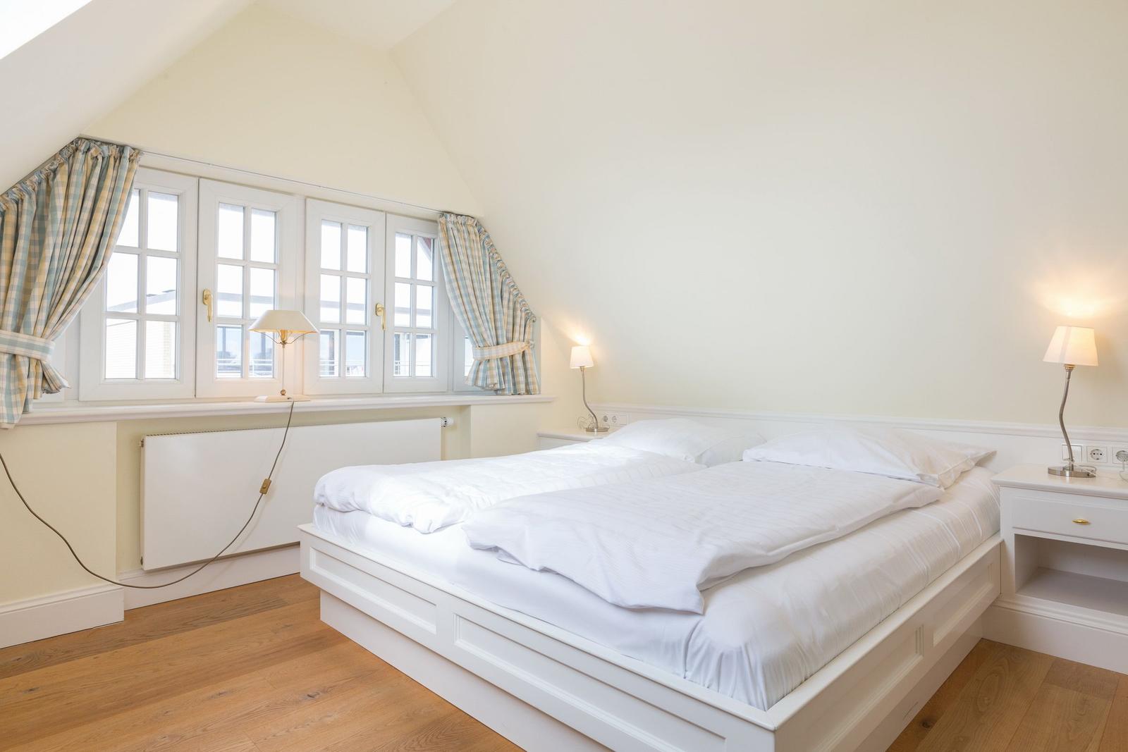 Bedroom with double bed, windows, and nightstand.
