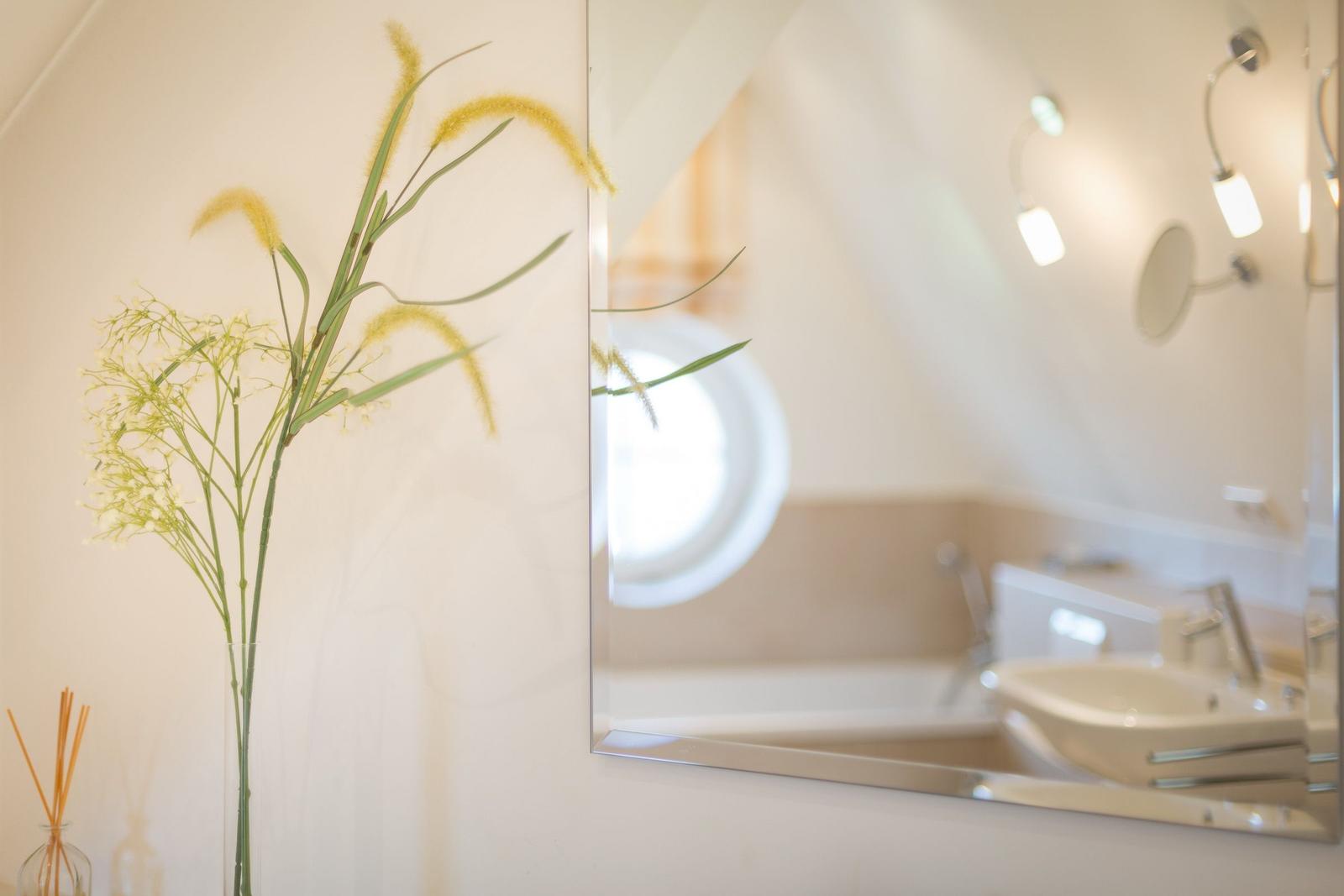 Bathroom with mirror, sink, and round window.