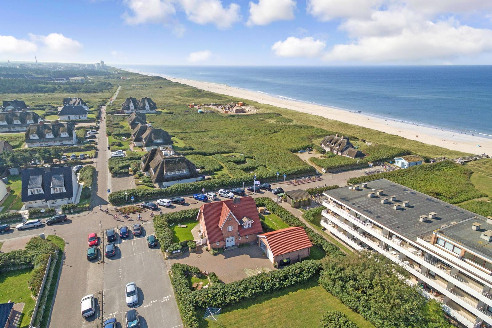 House with red roof near beach and green areas
