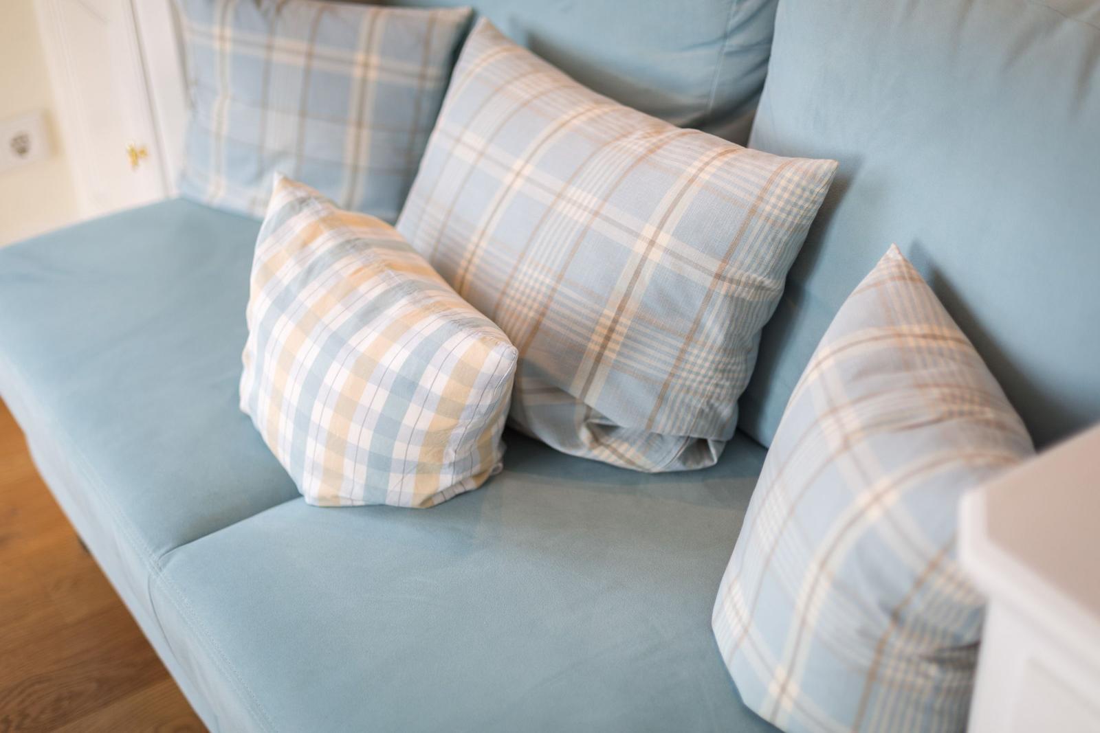 Blue sofa with checkered cushions in light colors.