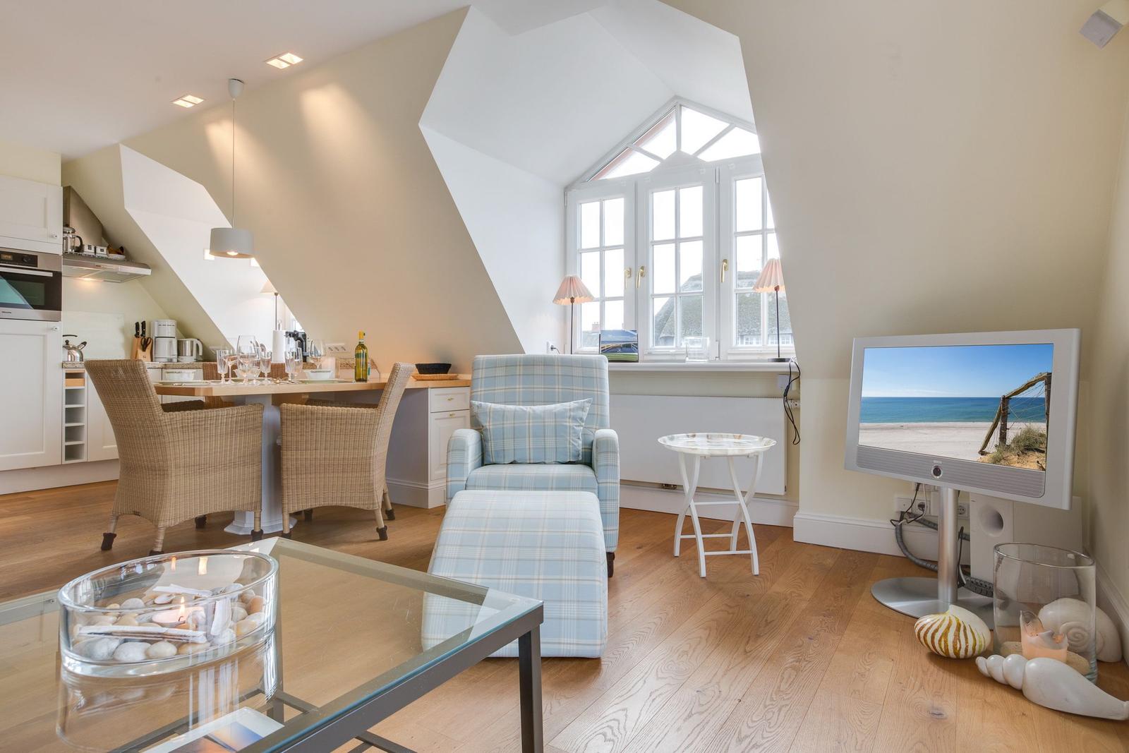 Living and dining area with TV, window, and wooden floor.