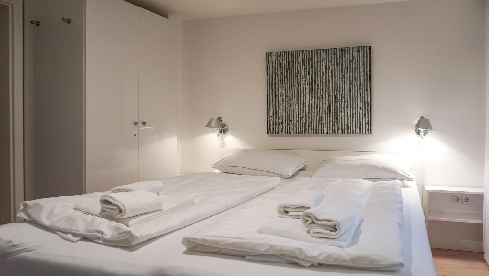 Bedroom with double bed, white bedding, and wall art.