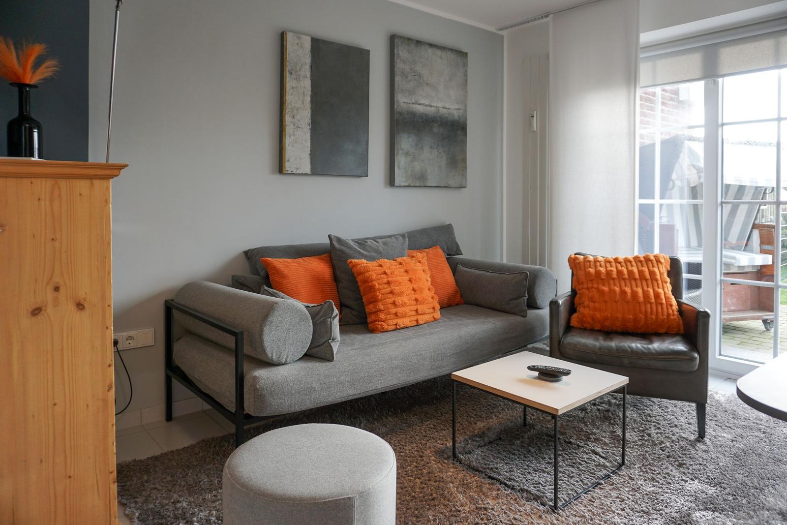 Living room with gray sofa, orange cushions, and wooden furniture.
