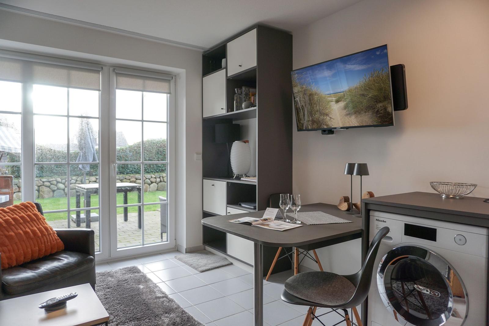 Living area with desk, TV, and view of the terrace.