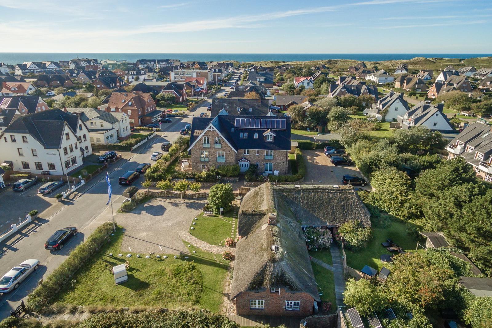 Dorf mit Häusern, Grünflächen und Blick aufs Meer