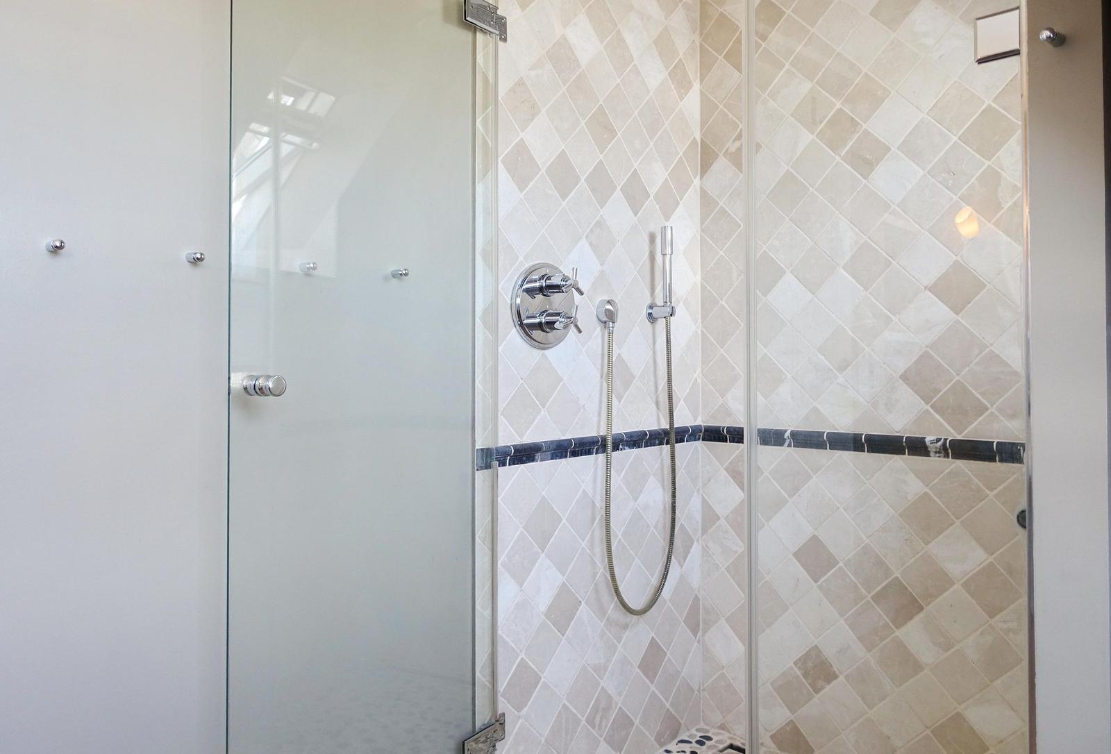 Shower enclosure with glass door and mosaic tiles