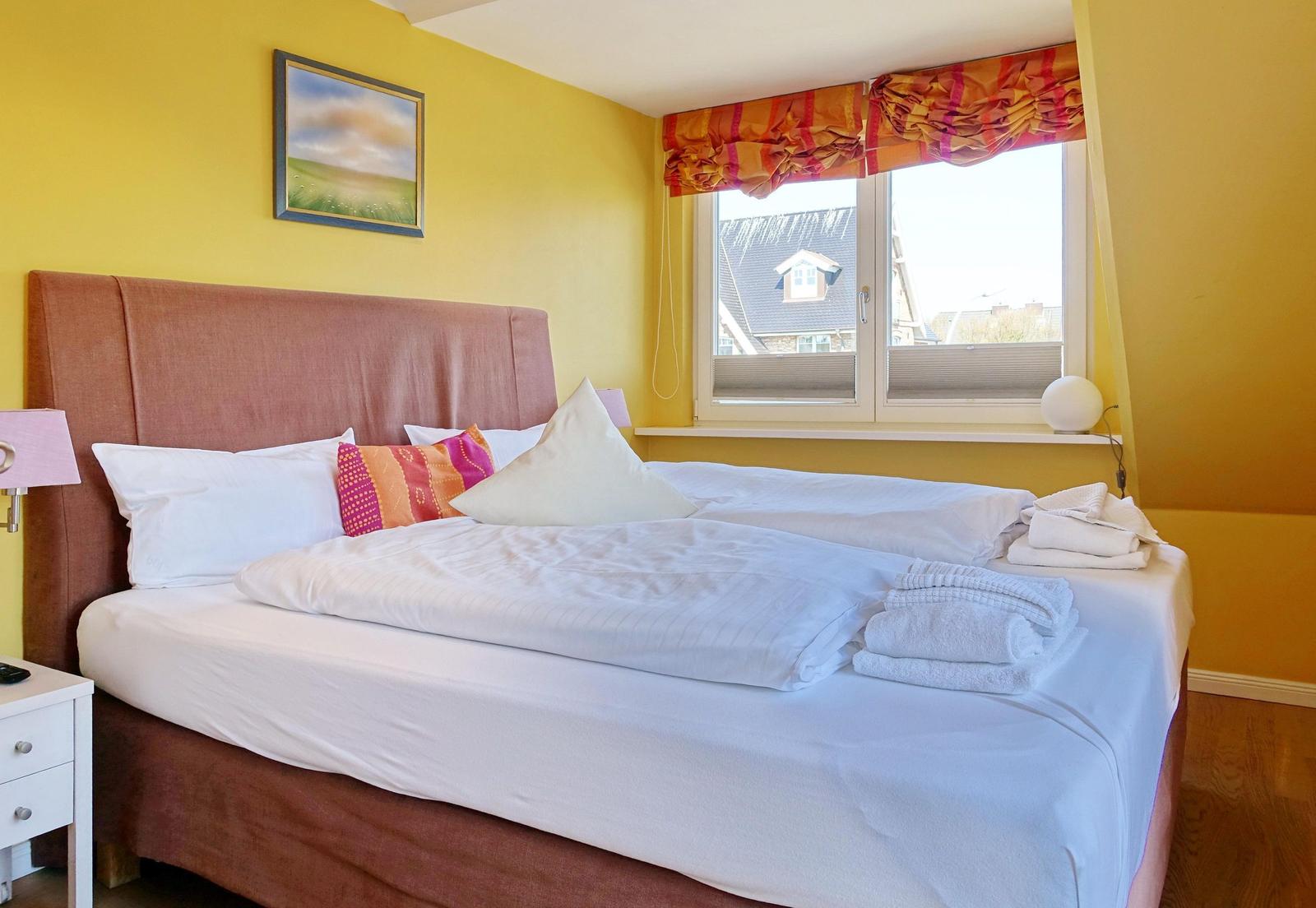 Bedroom with bed, window, and wall picture.