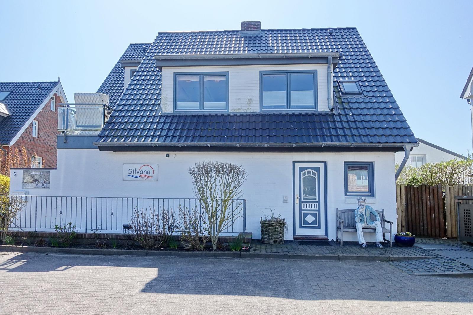 House with blue roof and white facade. Door and windows have blue frames.