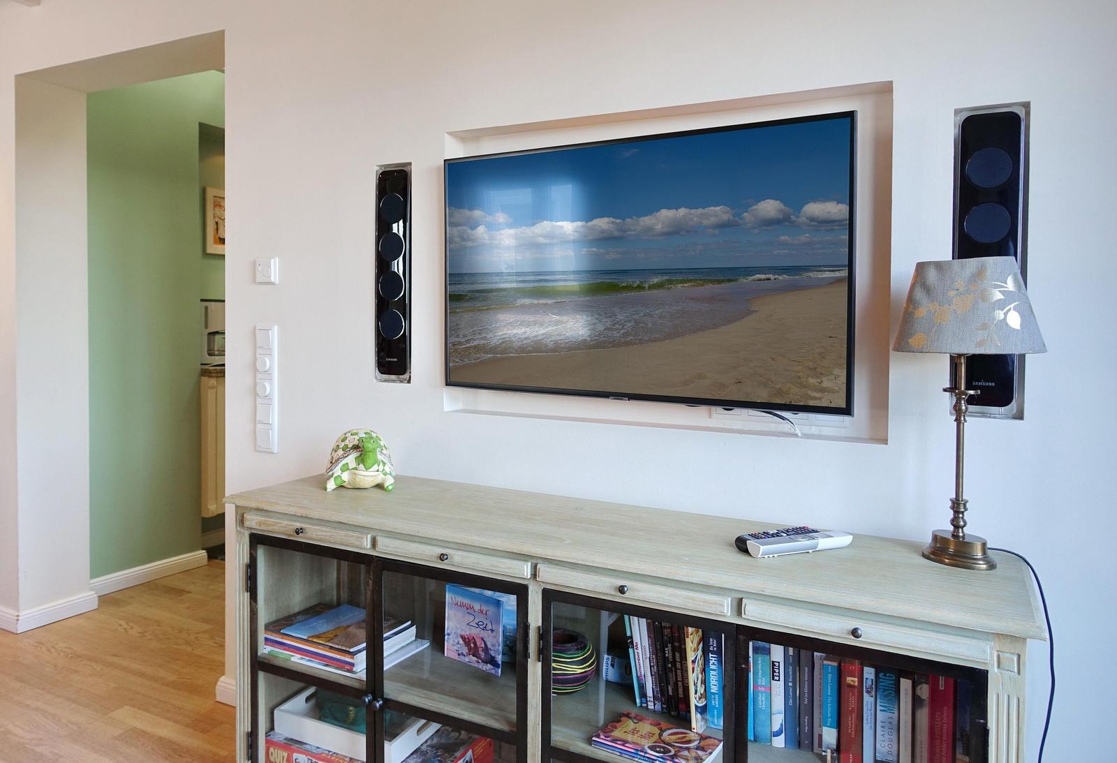 TV with beach scene, speakers, table lamp, and bookcase