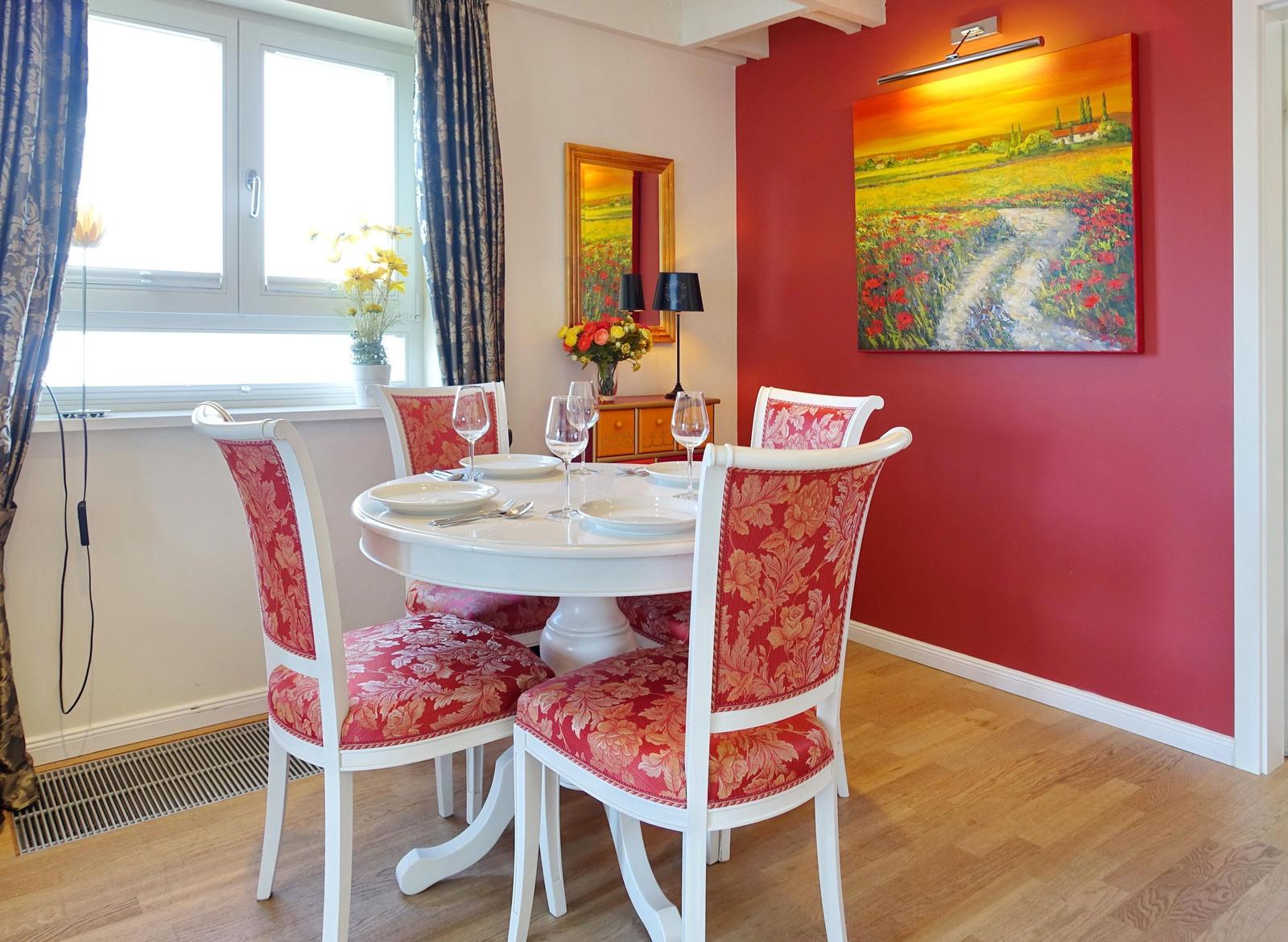 Red wall art above dining table with four chairs and window.