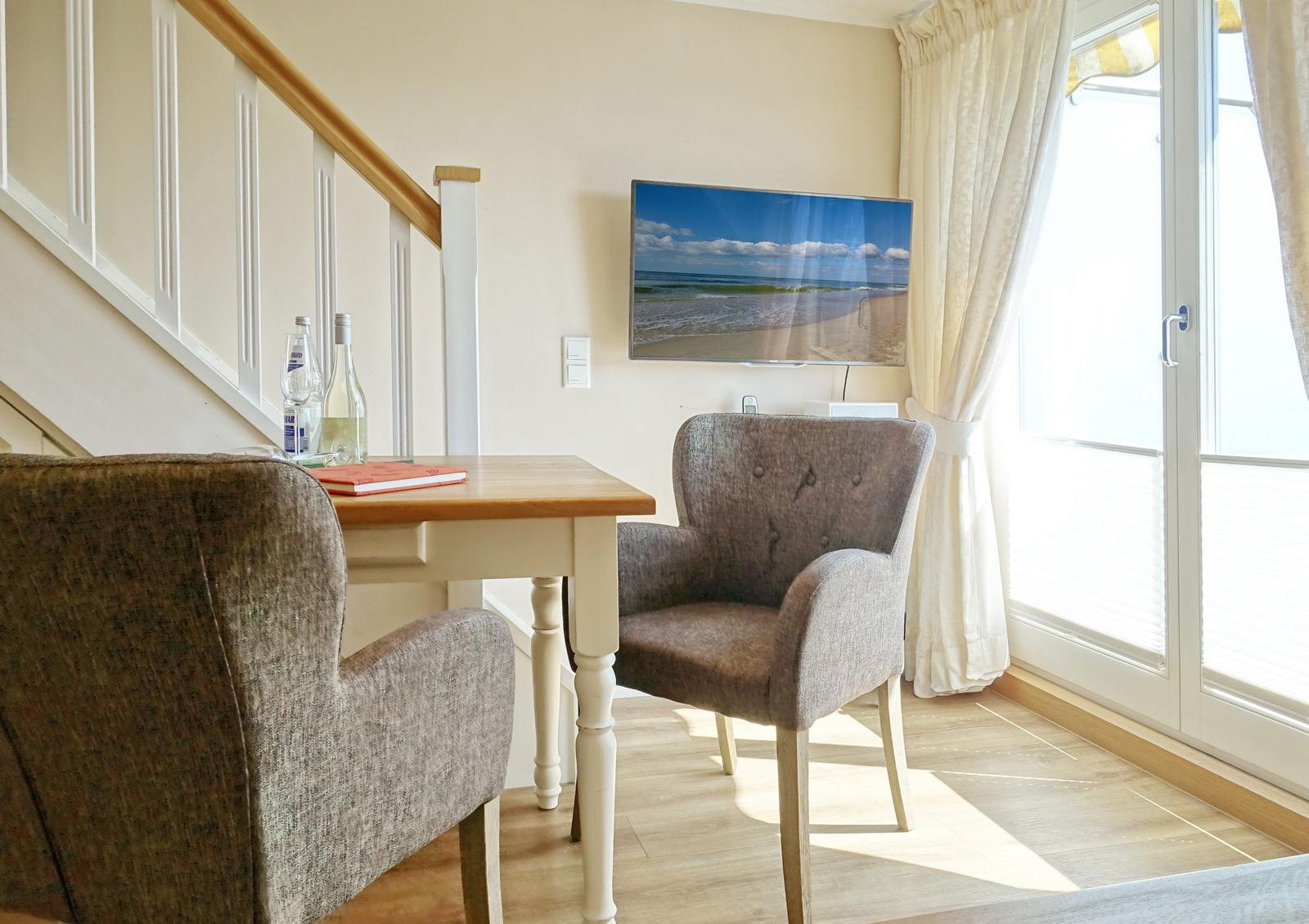 Dining table with two chairs, TV, and window with curtains.
