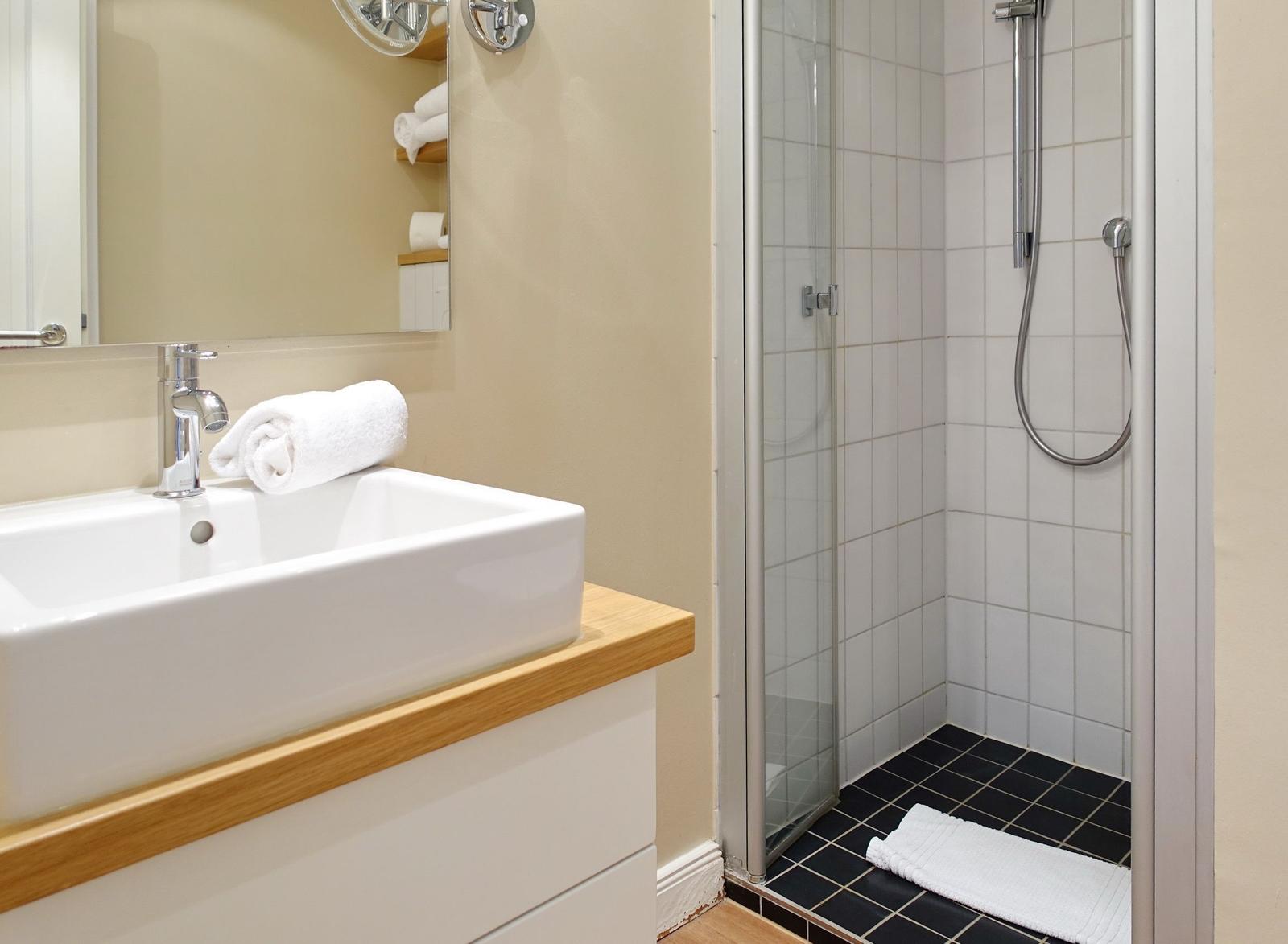 Bathroom with shower and sink on wooden countertop.