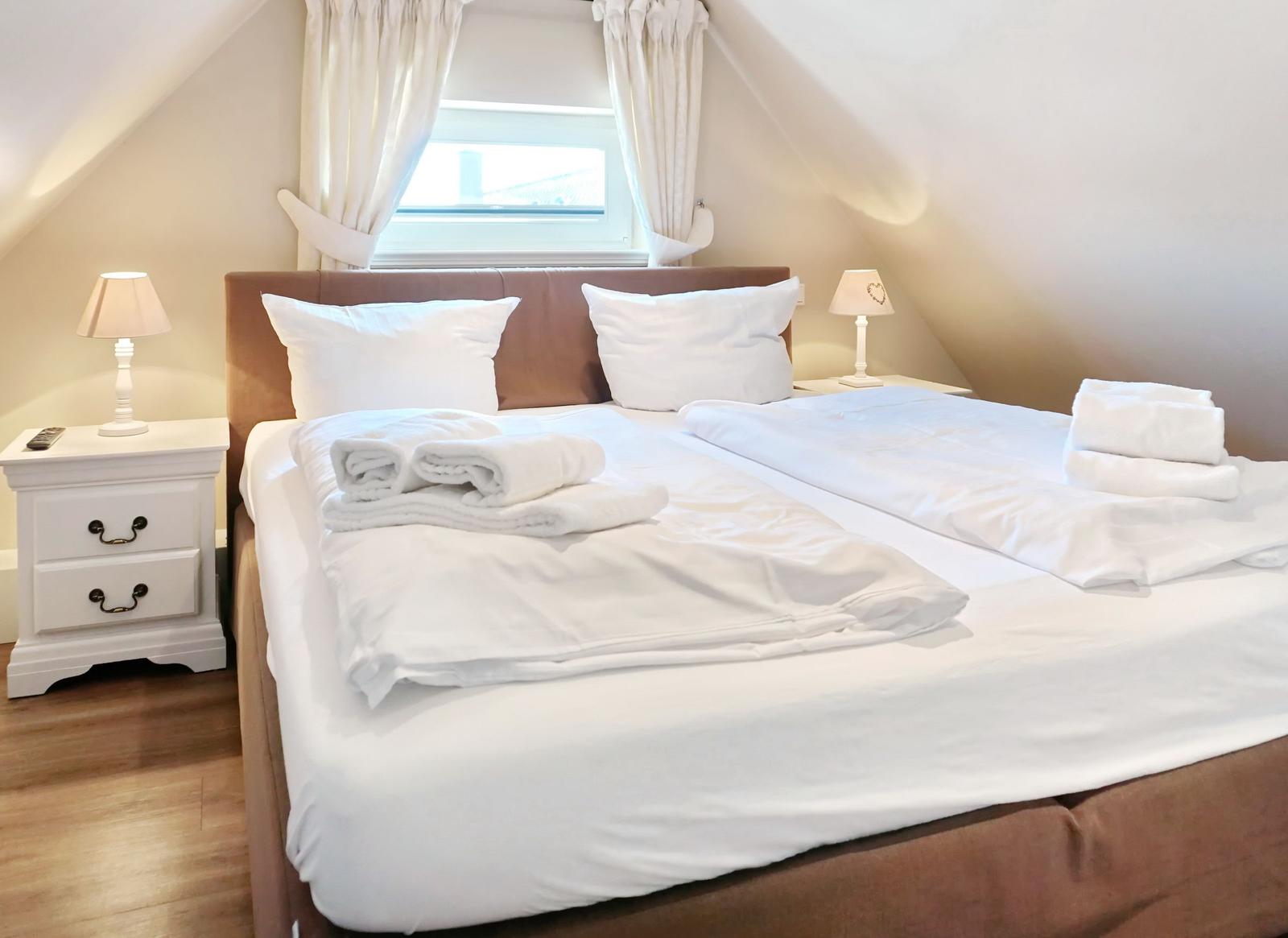 Double bed with white linens and two nightstands under sloped ceilings.