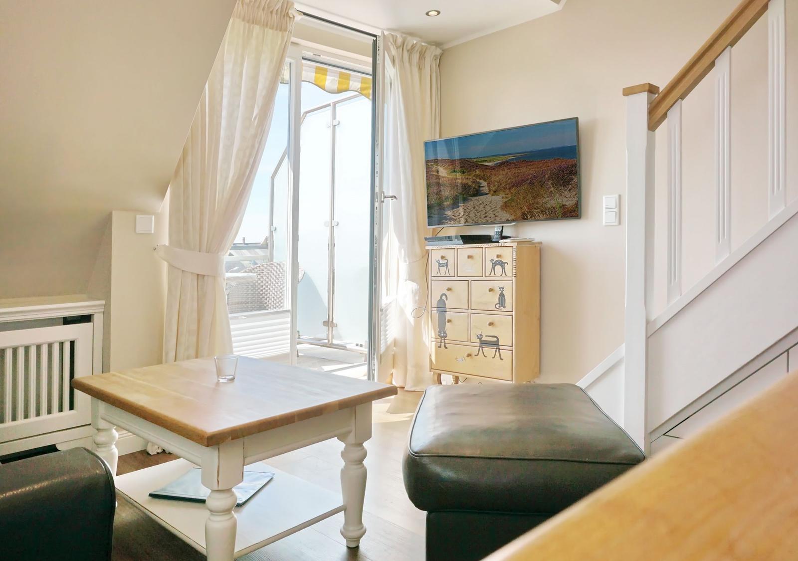 Living room with TV, table, and access to balcony.