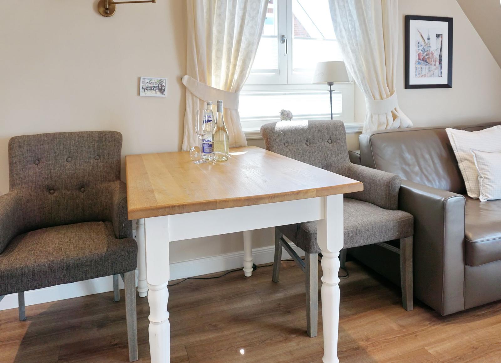 Wooden table with two chairs and sofa in room with window.