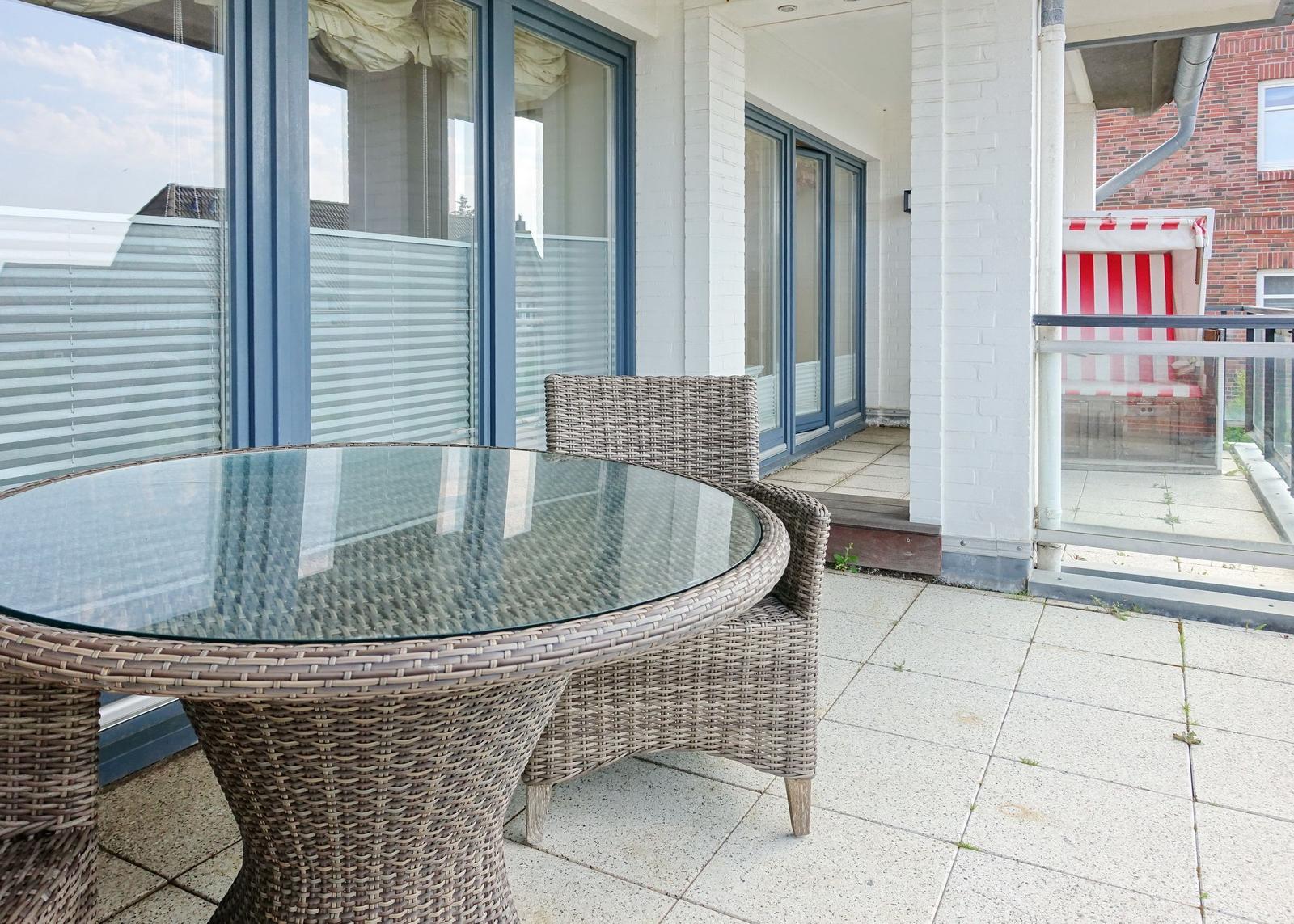 Terrasse mit runden Tisch und Stühlen, Glasfront und rotem Strandkorb