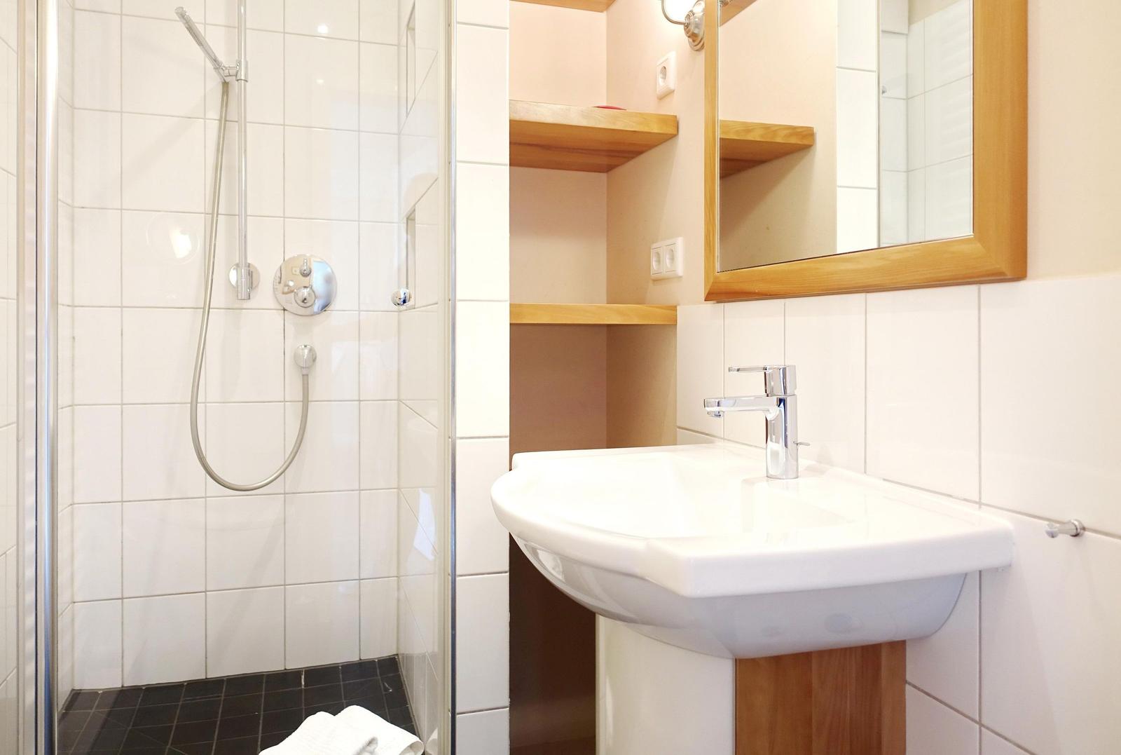 Badezimmer mit Dusche, Waschbecken und Spiegel