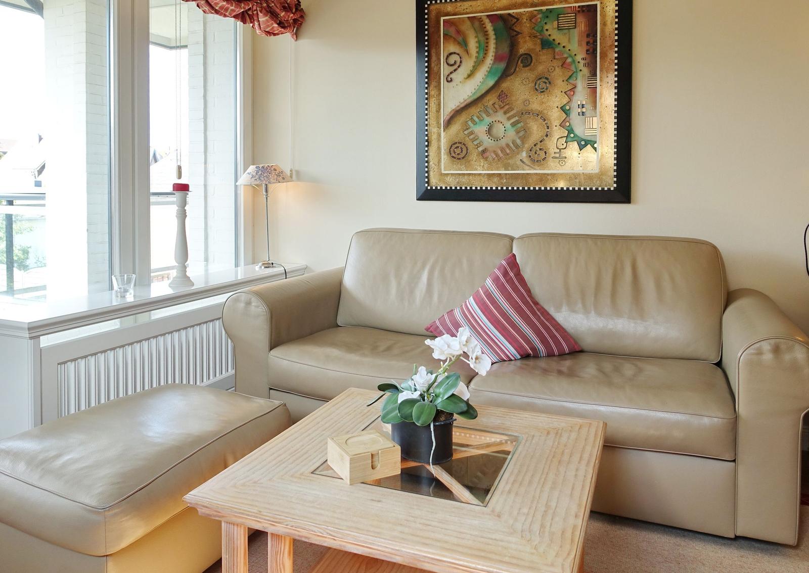 Ein Wohnzimmer mit einem Ledersofa, einem Beistelltisch und einem Fenster.