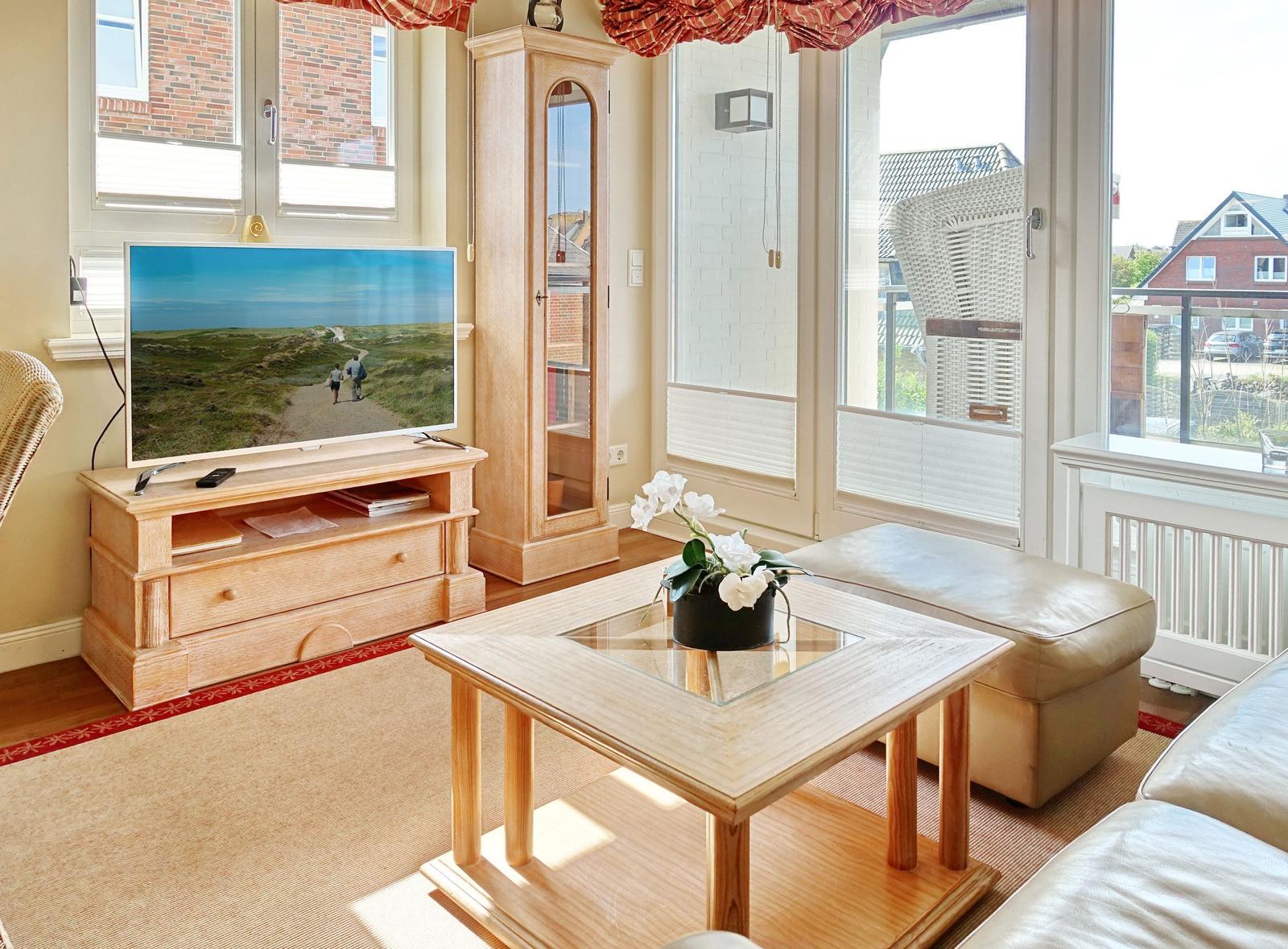 Wohnzimmer mit TV, Holzmöbeln und Blick auf Balkon