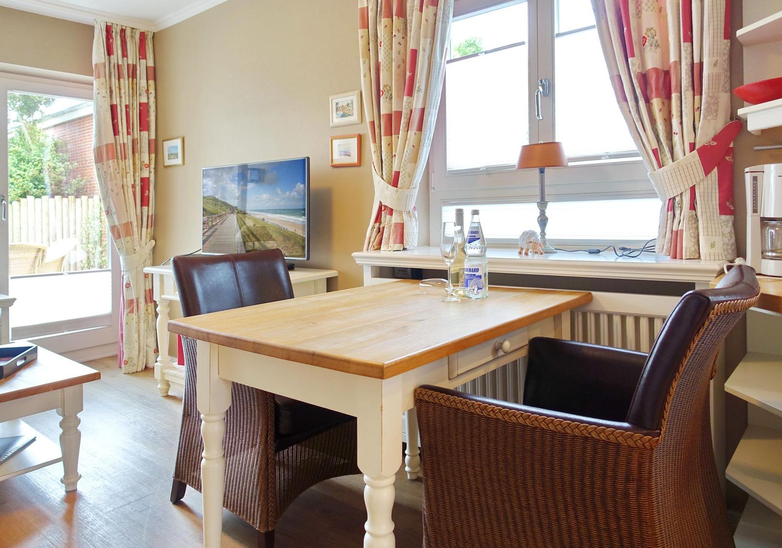 Dining table with two chairs by window with curtains