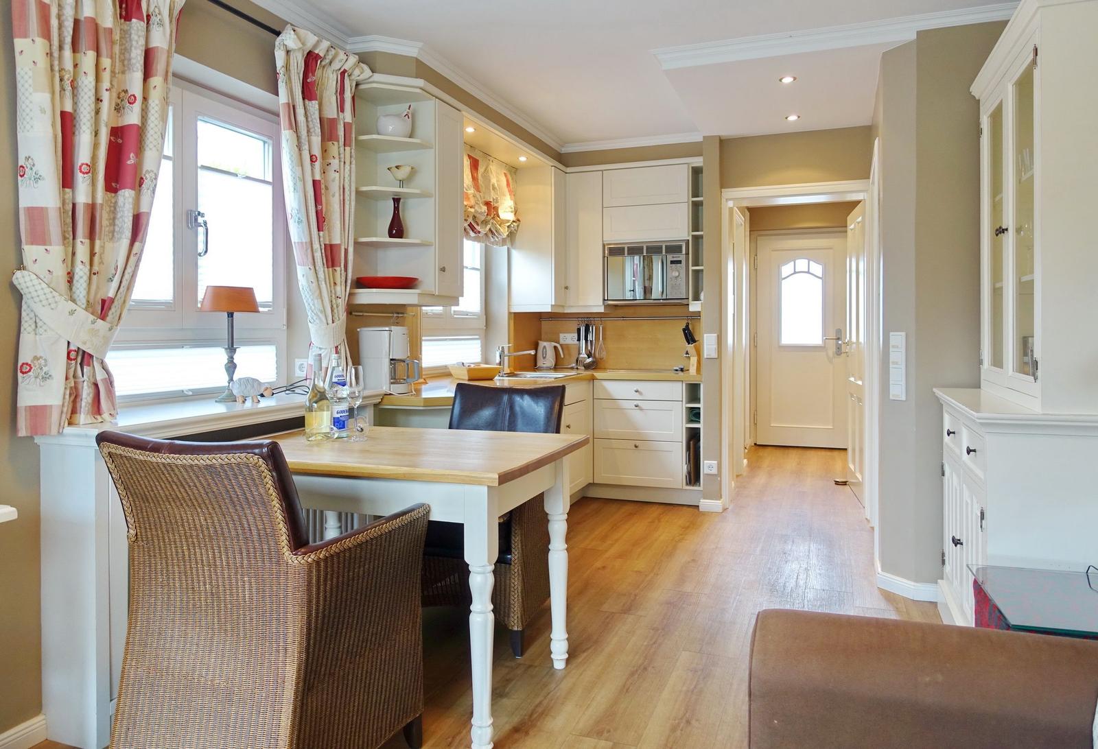 Kitchen with dining area, wooden floor, and window with curtains