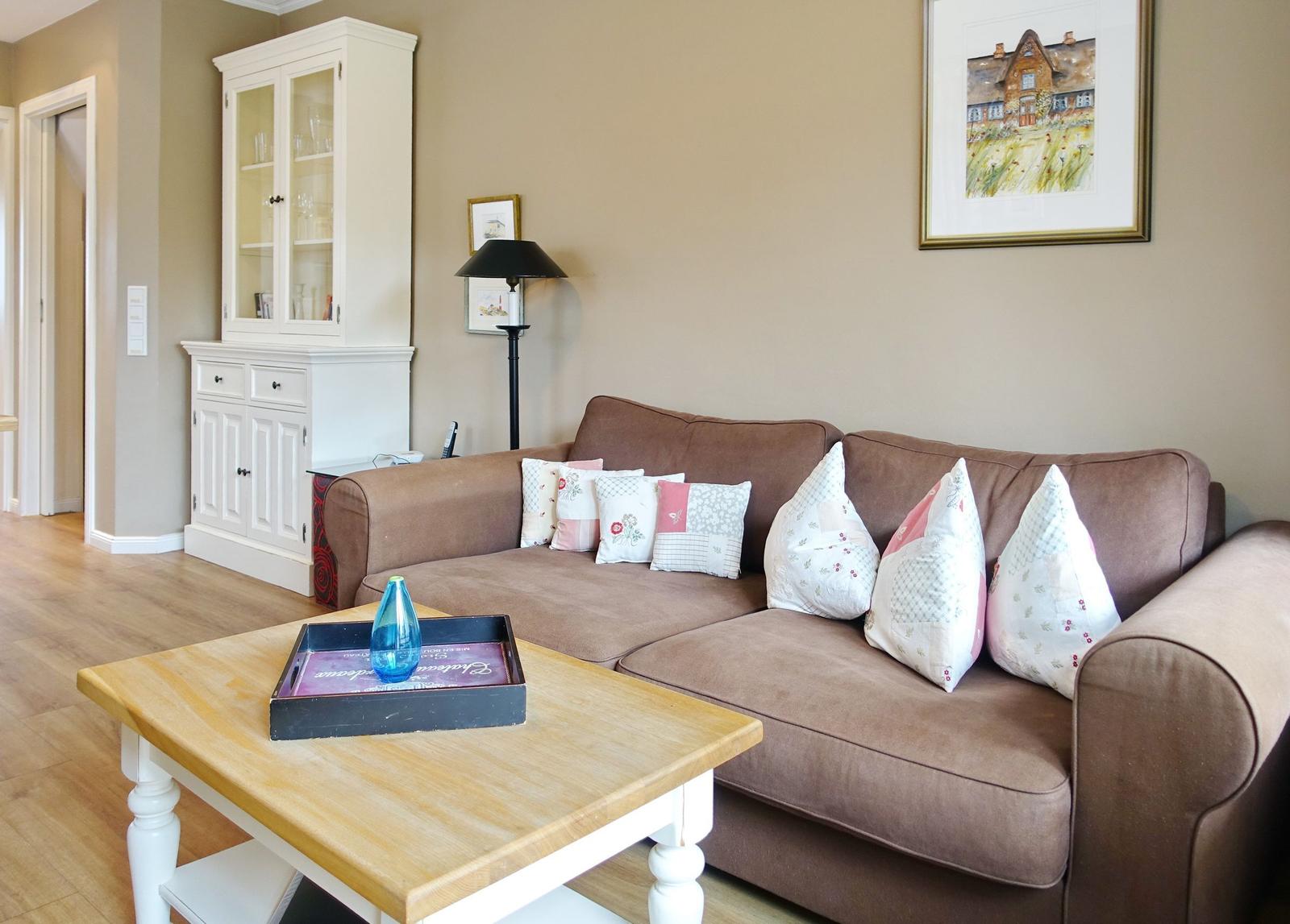 A living room with a brown sofa, cushions, and wooden table.