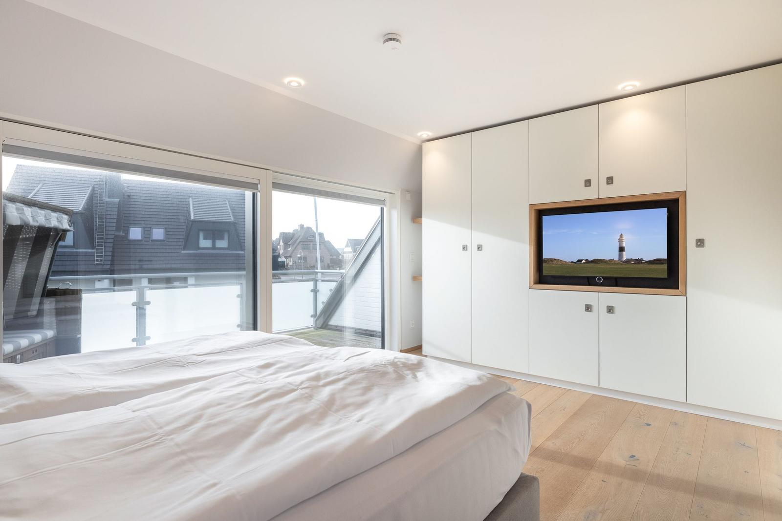 Bedroom with bed, TV, and balcony view.