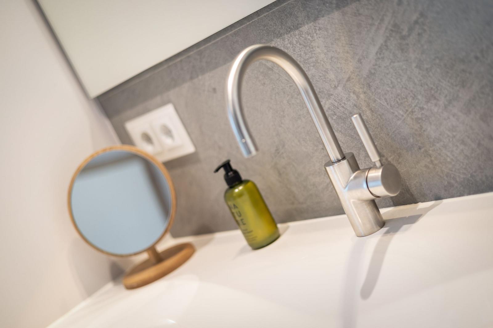 Sink with modern faucet and green liquid soap dispenser.