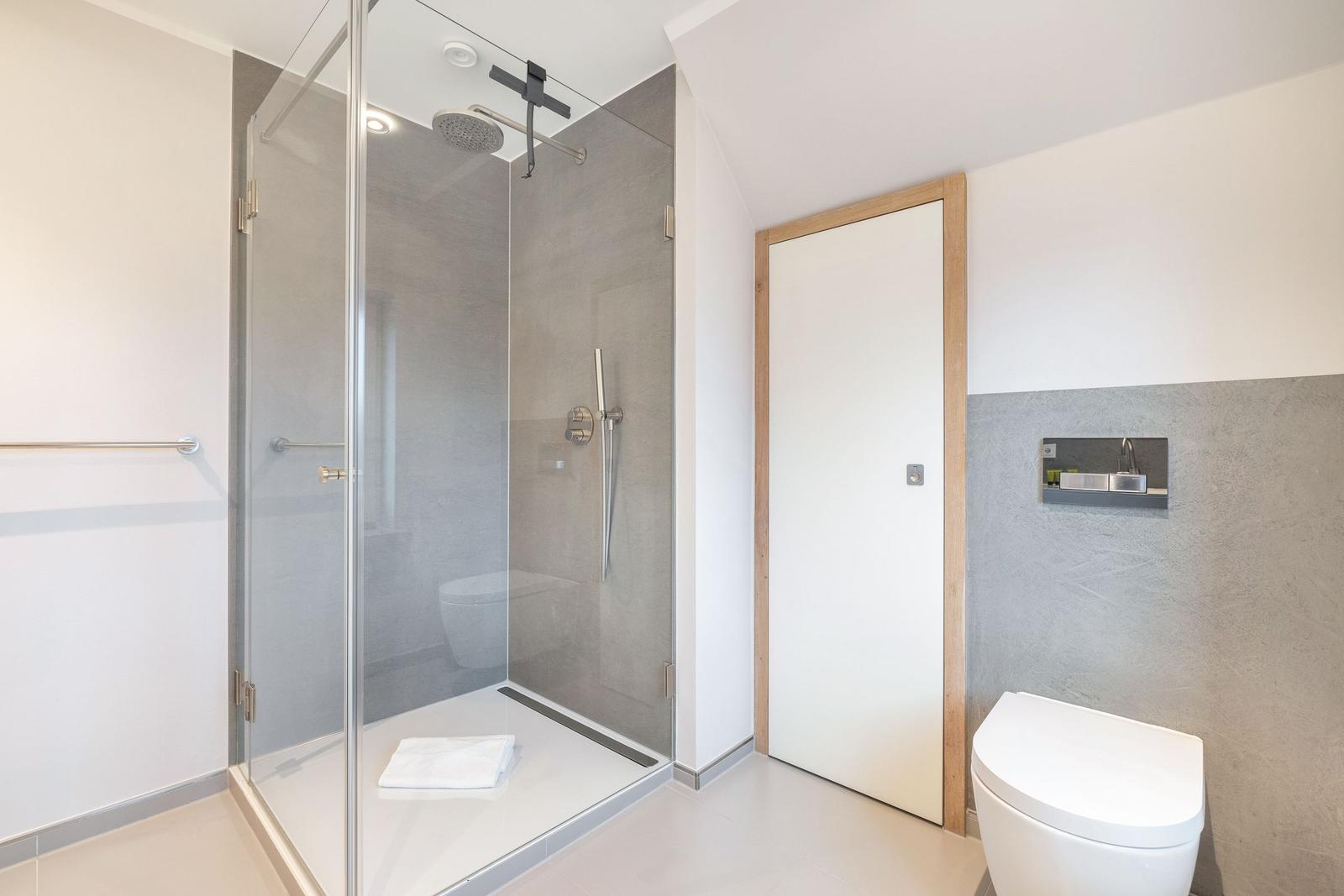 Shower with glass enclosure, toilet, and sink area