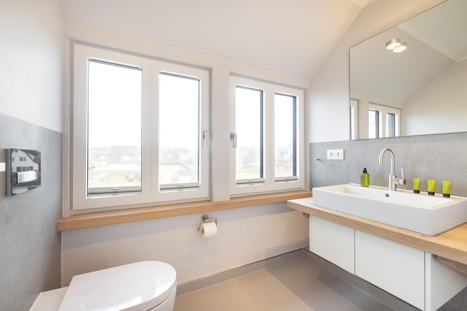 Bathroom with windows, sink, and toilet.