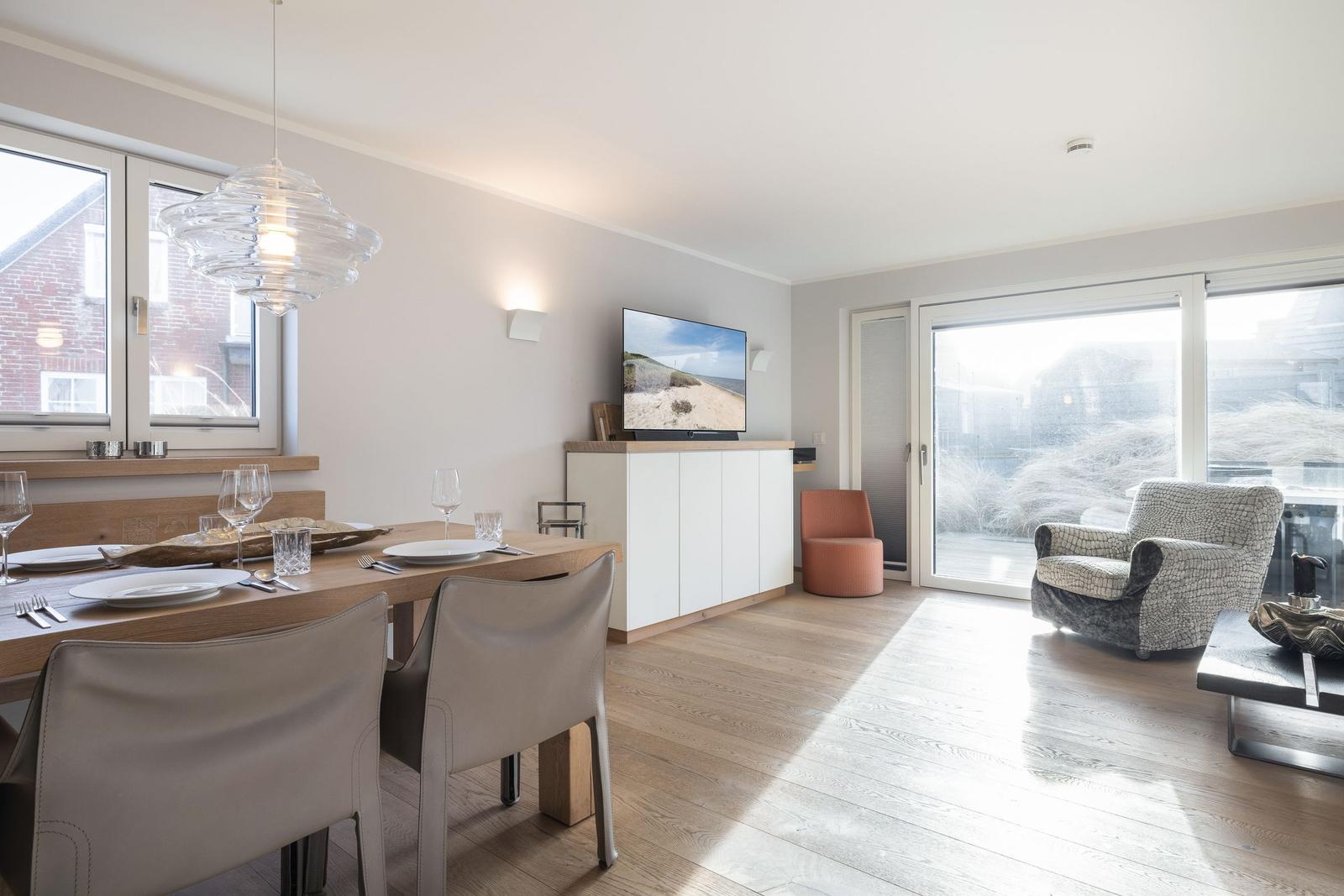 Dining area with table and chairs, TV, and seating in living area.