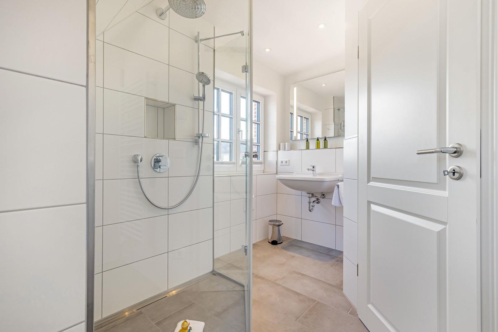 Badezimmer mit Dusche, Waschbecken und Fenster