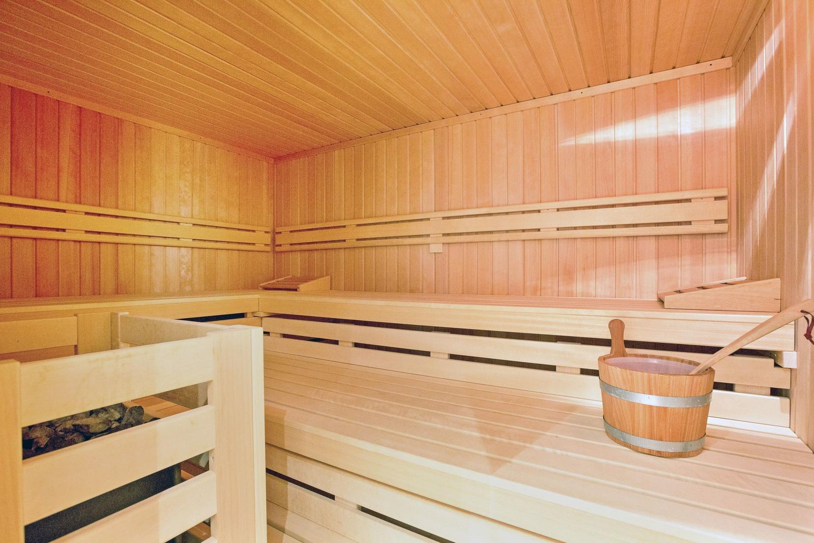 Sauna mit Holzbänken und Eimer mit Löffel