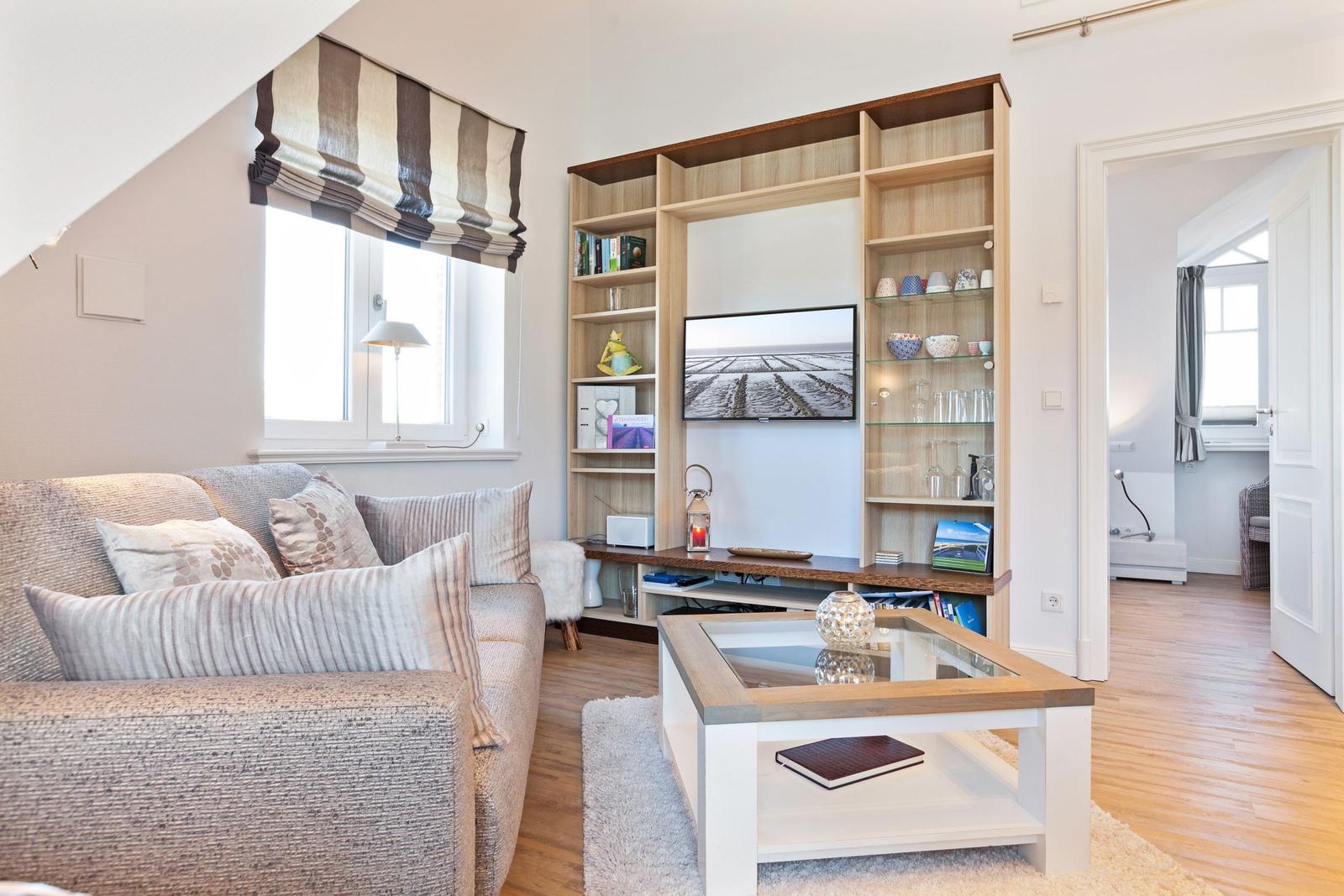 Wohnzimmer mit Sofa, Couchtisch und integriertem Bücherregal mit Fernseher.