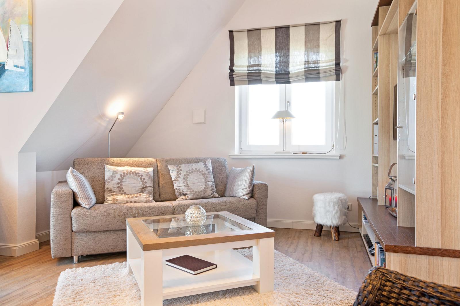 Wohnzimmer mit Sofa, Couchtisch und Bücherregal unter Dachschräge.