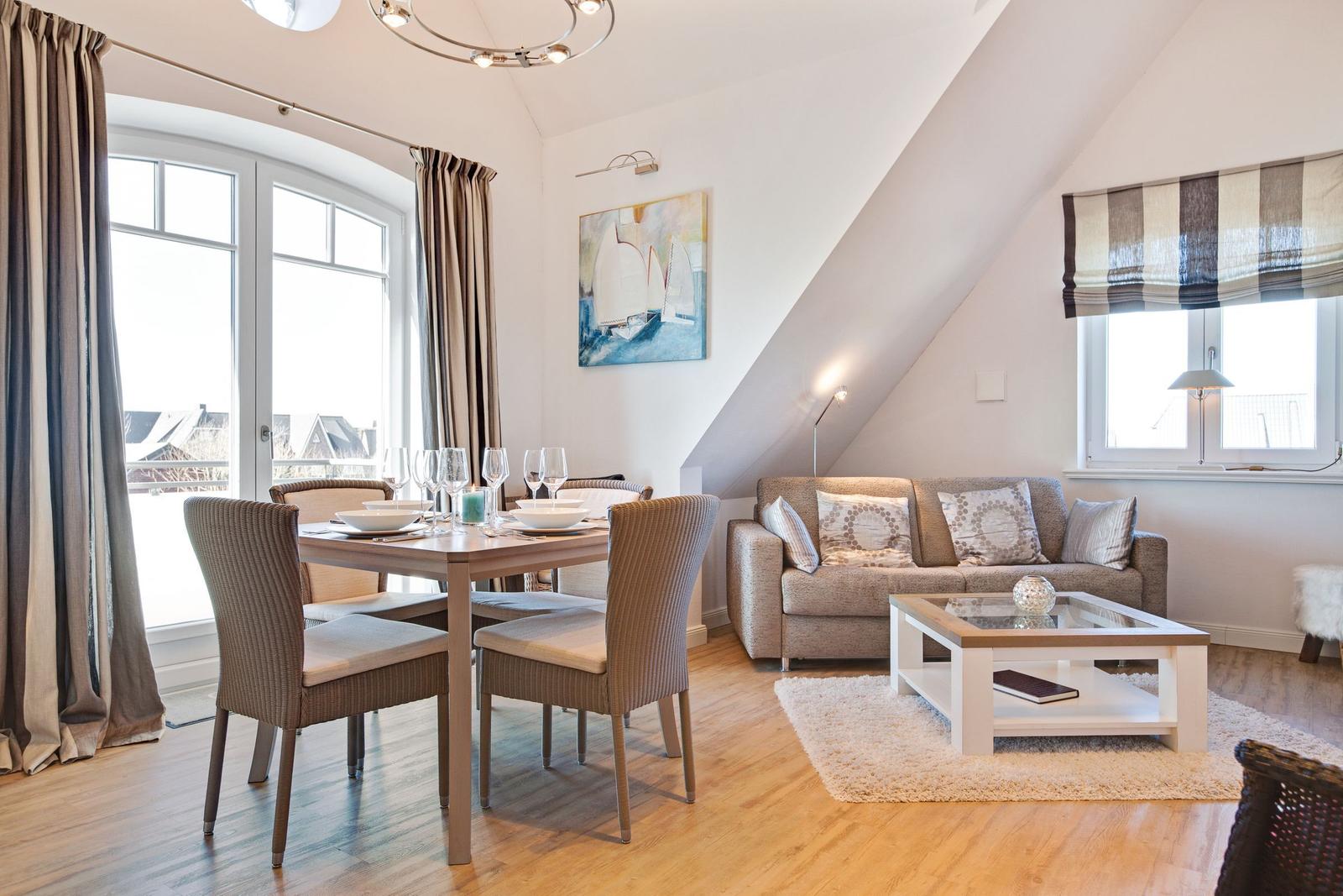 Wohn- und Essbereich mit Sofa, Tisch und Stühlen unter Dachschrägen.
