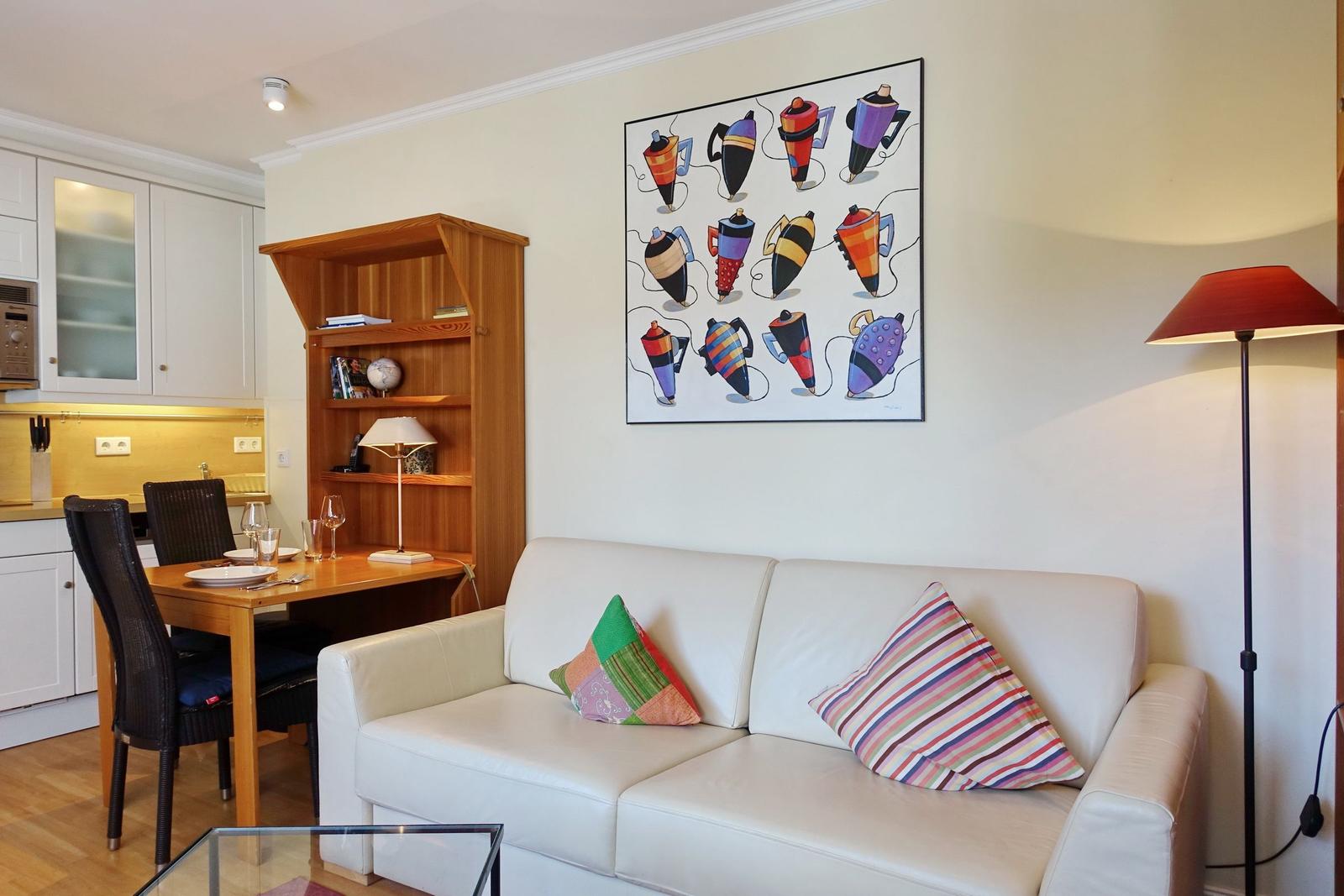 Living room with sofa, dining table, and wall art featuring coffee machine motifs.