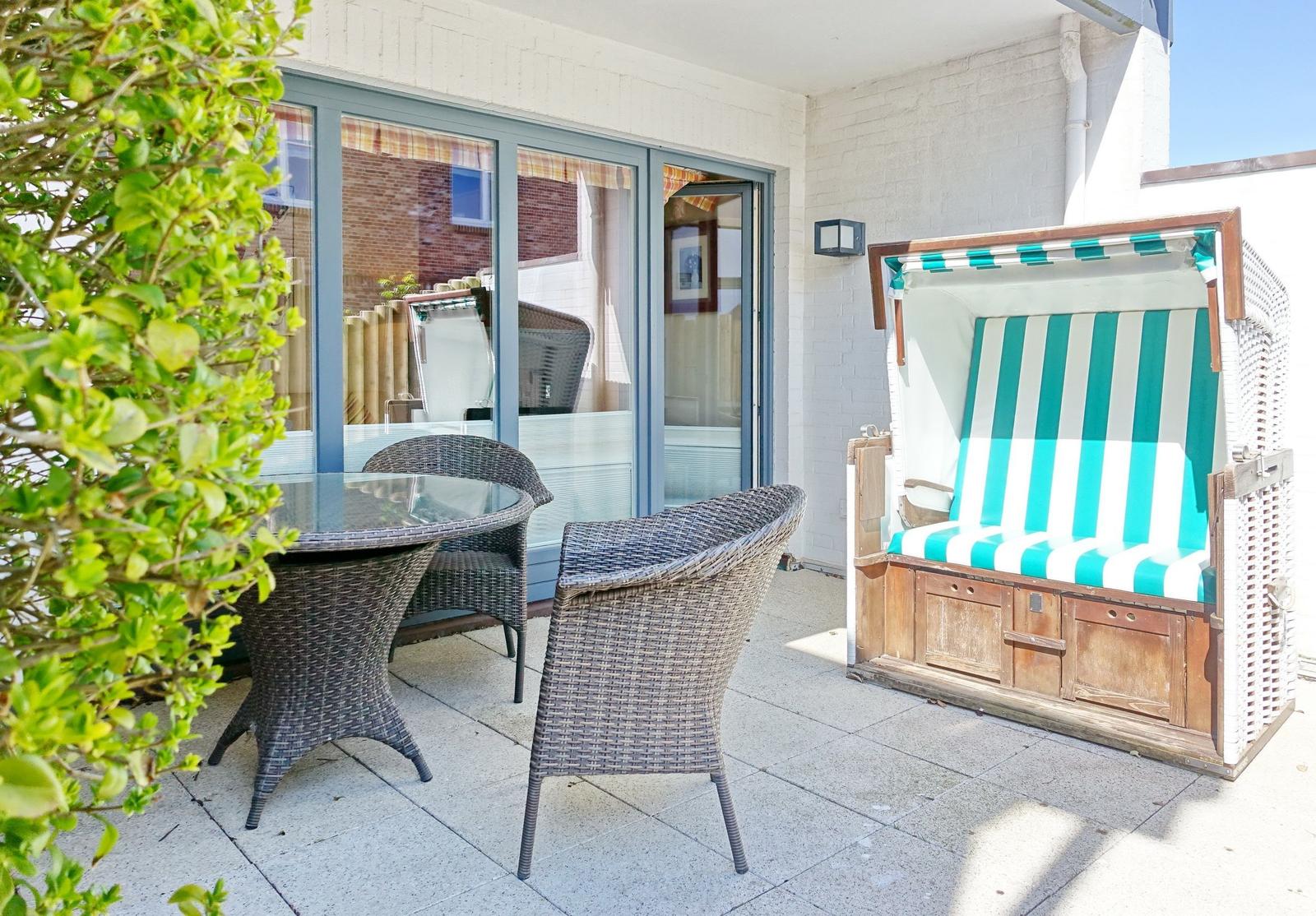 Terrace with garden furniture and beach chair with green-white stripes.