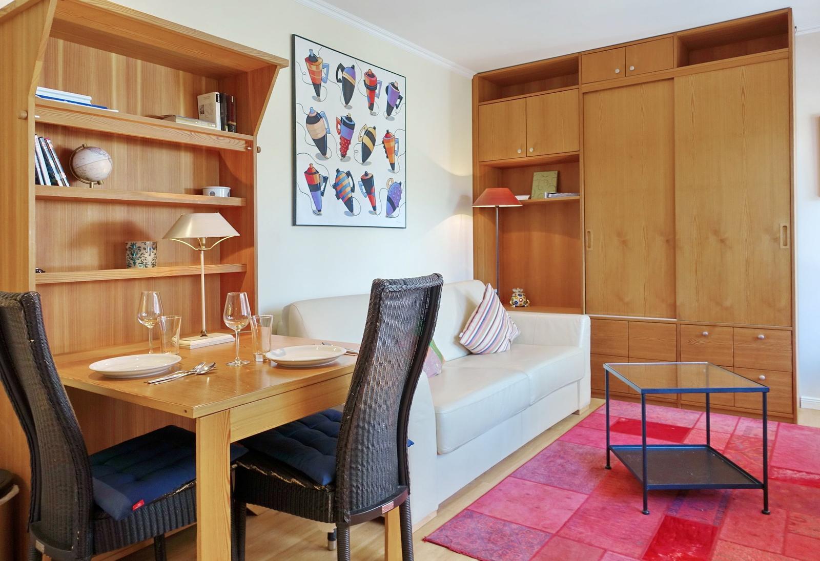 Living room with dining area, sofa, bookcase, and wooden furniture.